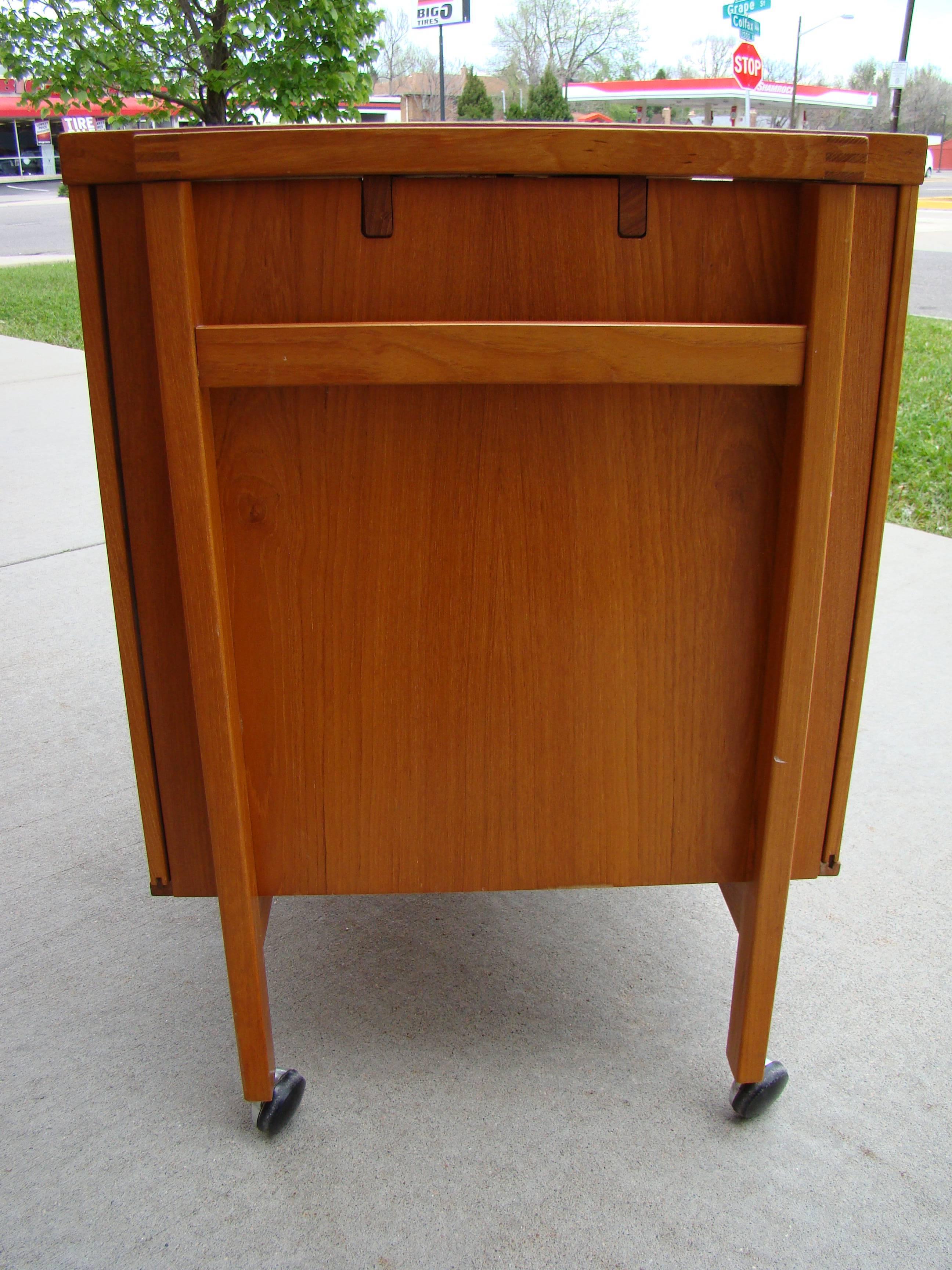 Danish bar cabinet in teak offers discreet liquor storage, and working flat/serving/display space in a beautiful teak cabinet on castors. Ingenious
design opens at center to reveal bar storage and glass shelf for glassware.
Black laminate flat