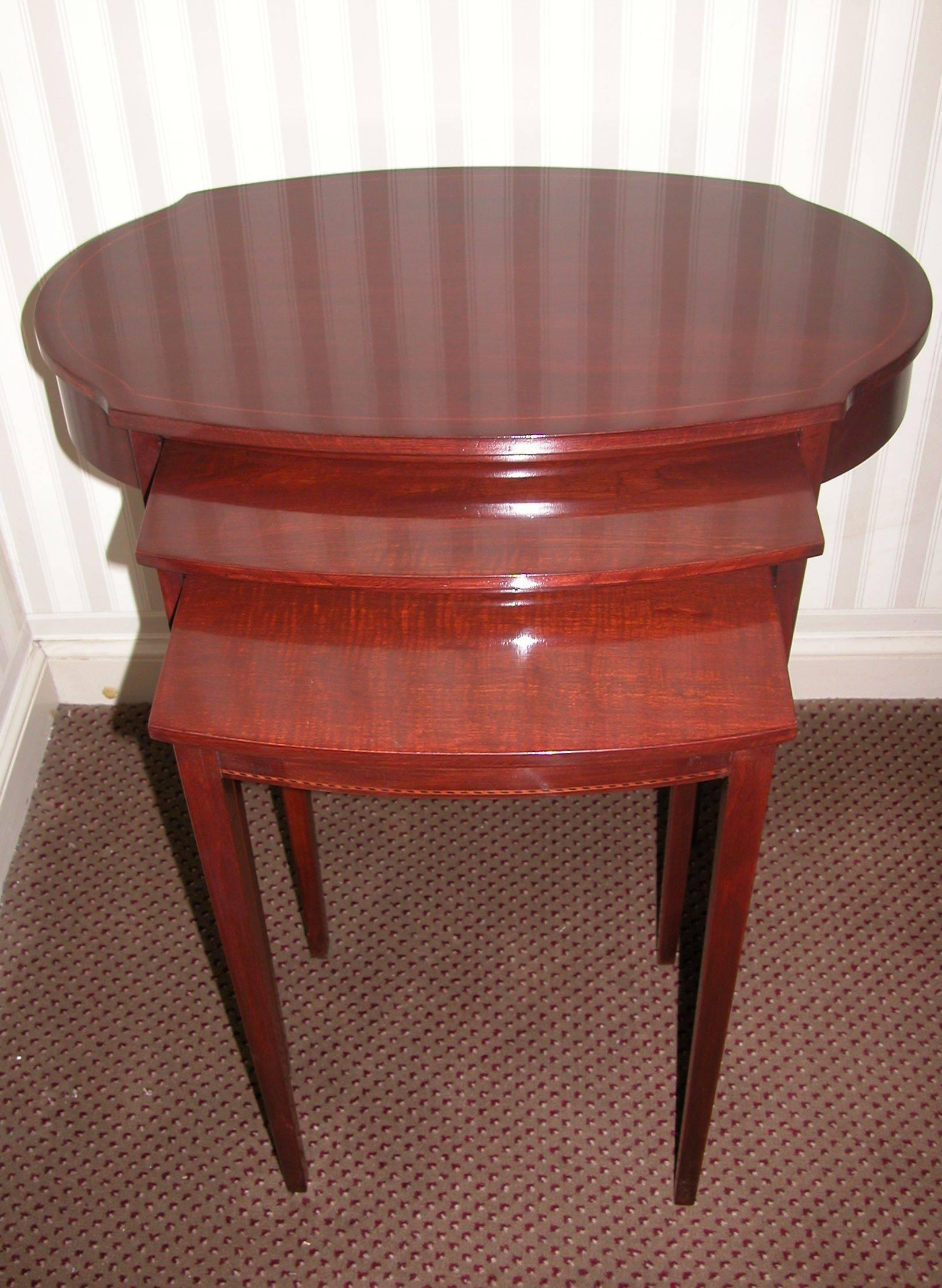 Nest of three tables in oval and rectangular form on straight- tapered legs. Recently refinished and in excellent condition. Middle tray is 17.5