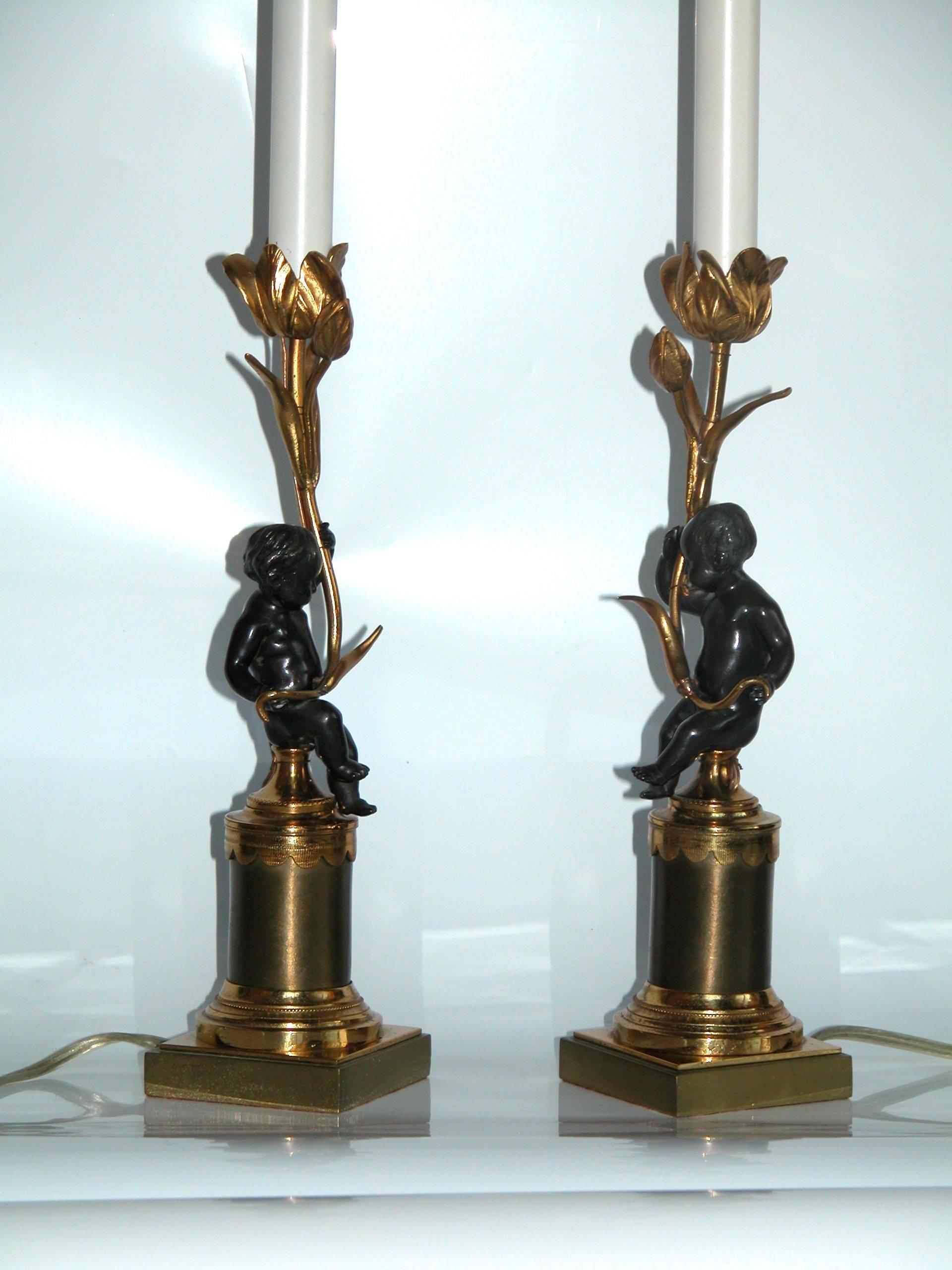 Pair of exquisite dressing table lamps in bright gilt finish with dark bronze finished cherubs. The dimension to the top of the gilt floral candle cup is 11 3/4
