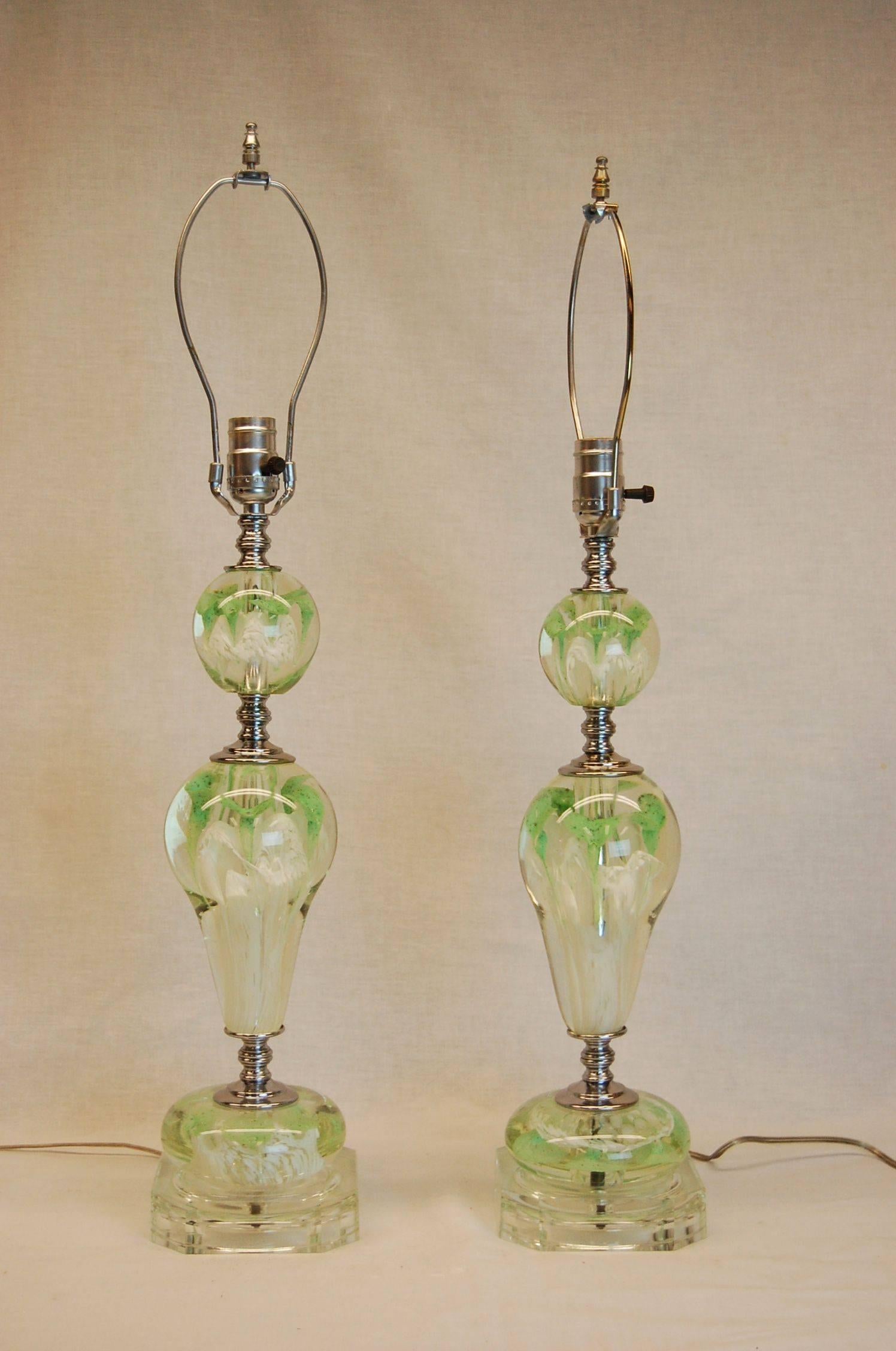 Pair of mint condition glass lamps with green and white floral paper weight art glass balls. The pair of shades were custom-made silk and have special rushing trim top and bottom. Possibly St. Clair Glass Co.