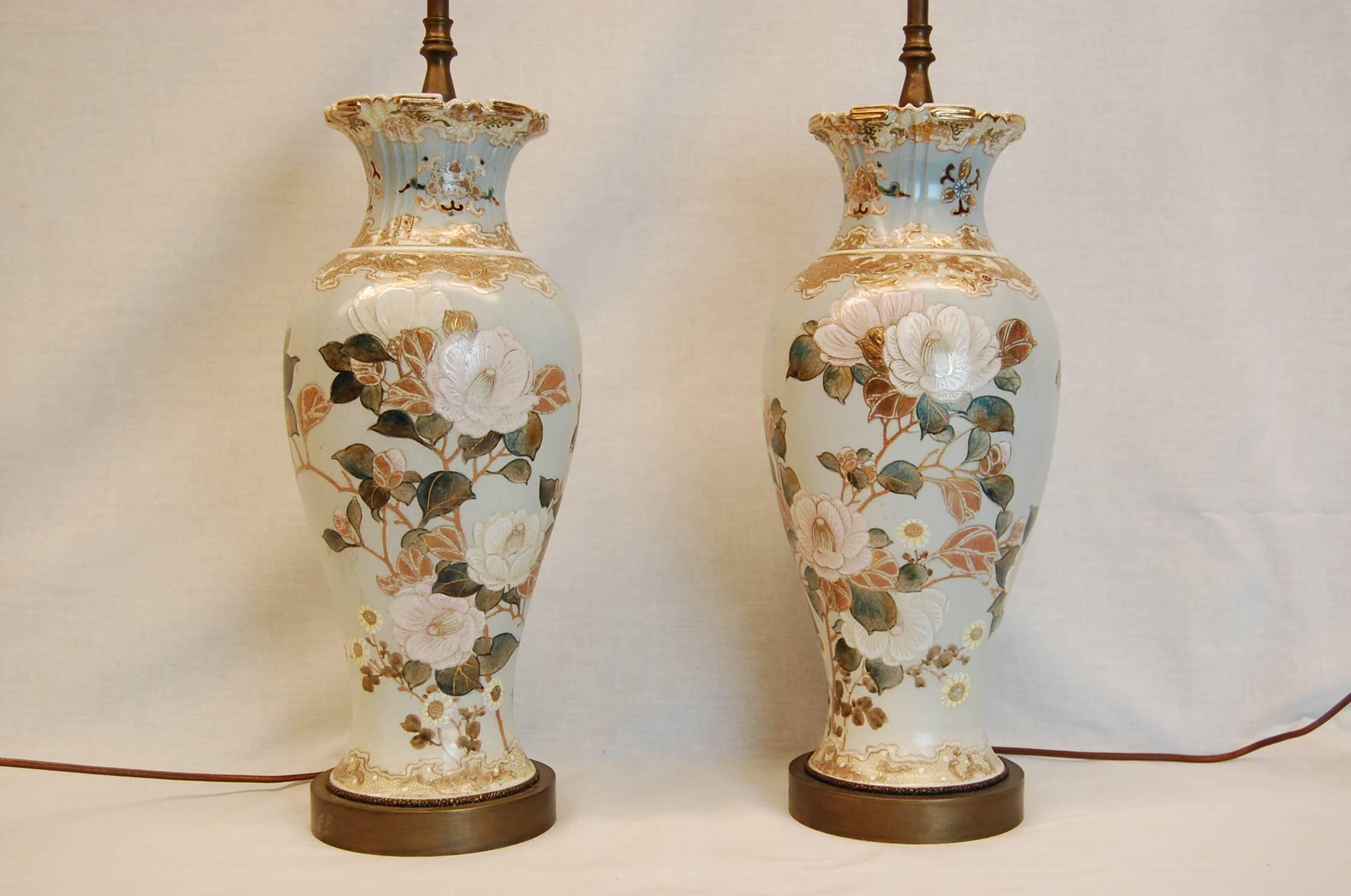 Pair of lamps with beautiful Magnolia blossoms decorations on a pale blue background. The urns themselves measure 15 1/4 inches tall. Excellent condition.