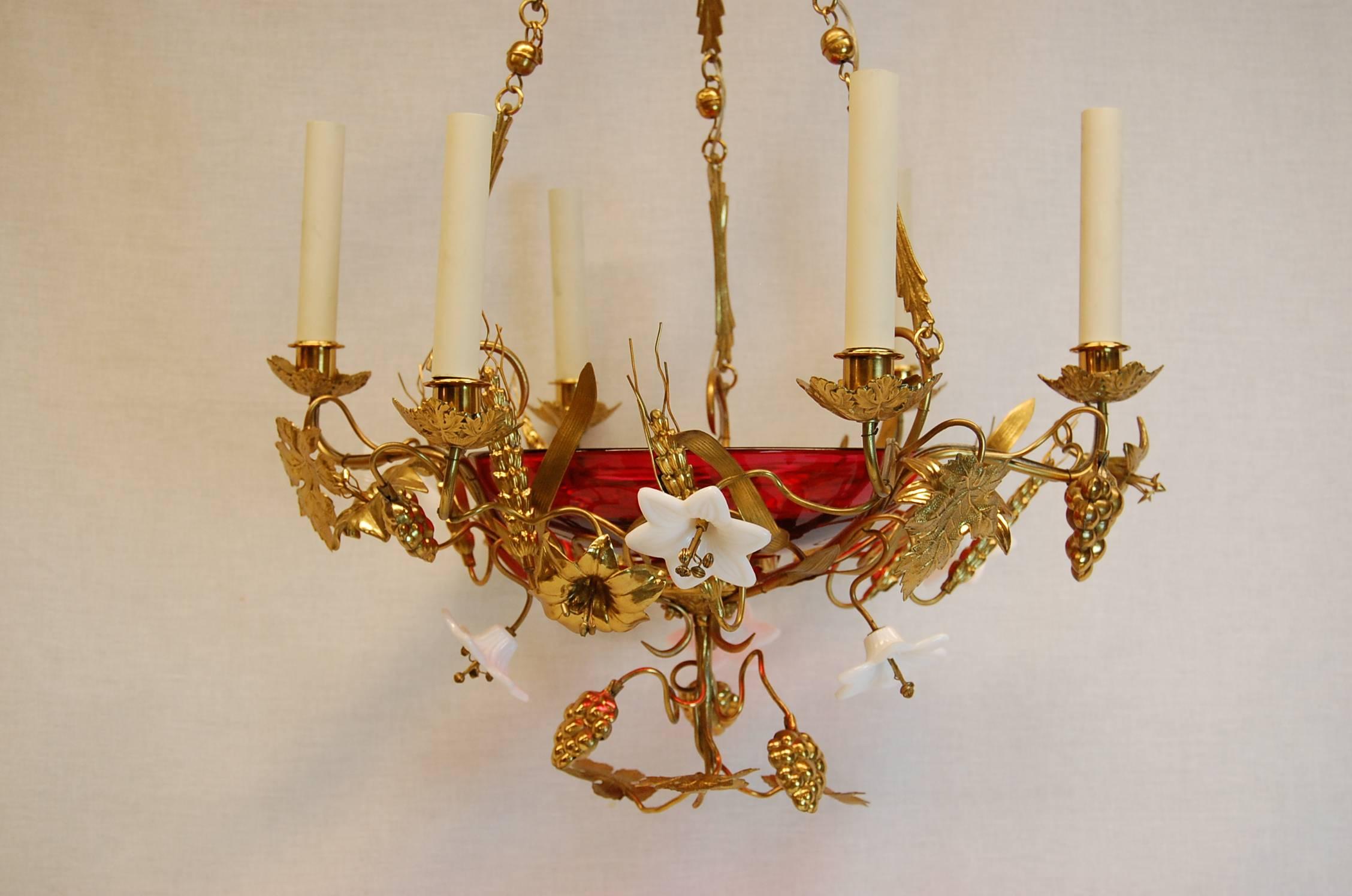 Beautiful six light chandelier with white opaline glass lilies and stamped brass grape clusters, wheat and leaves in excellent condition. The centre bowl is clear cranberry glass. The overall dimensions are: 19