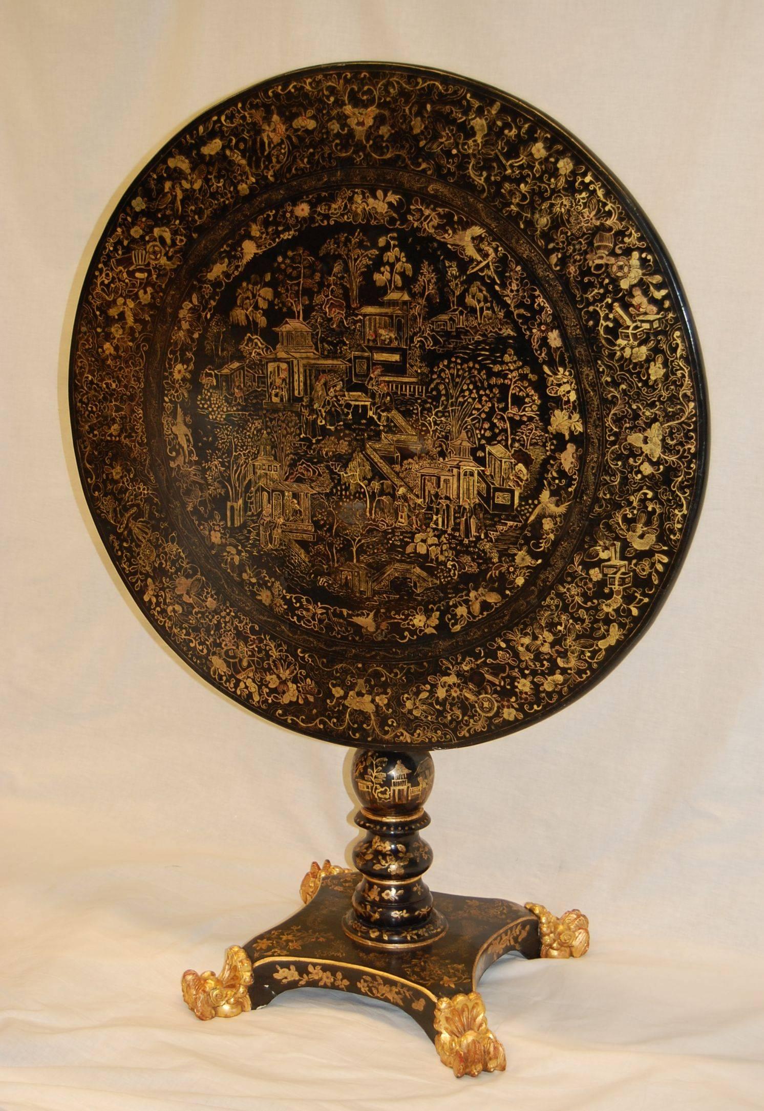 Exquisite black lacquered gold decorated dessert table with center column and lion paw feet in gold leaf finish. Excellent tight condition.