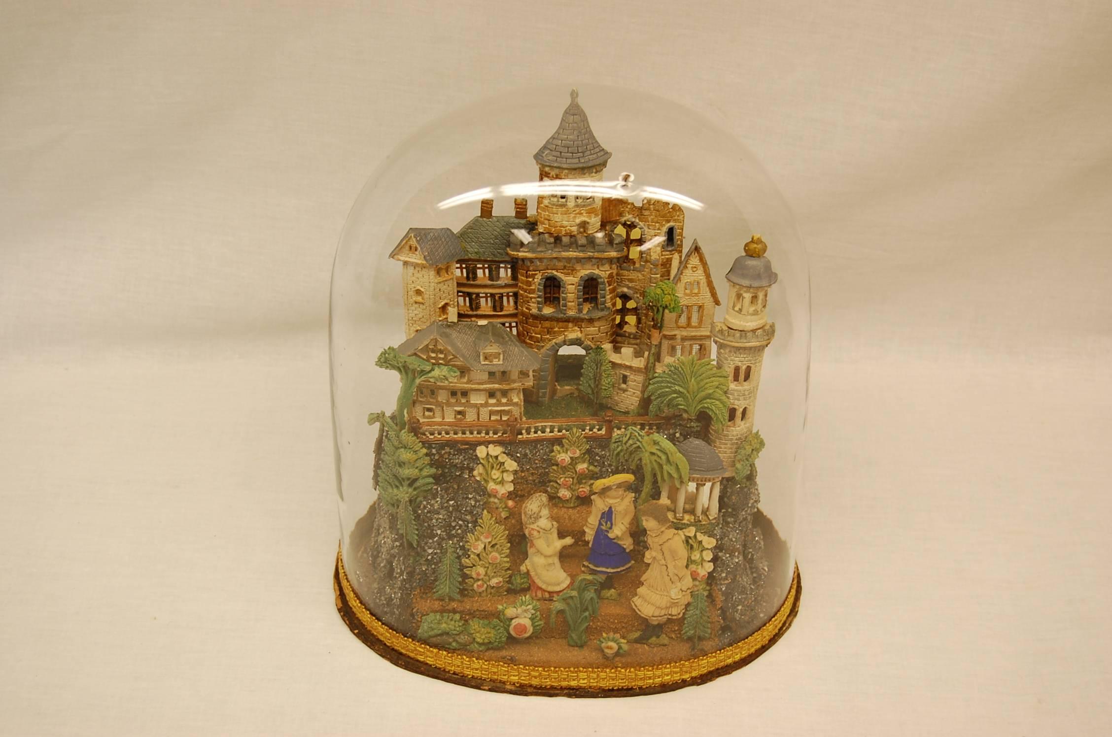 European castle, trees, bushes, people and crushed glass comprise this wonderful diorama under the original glass dome.
