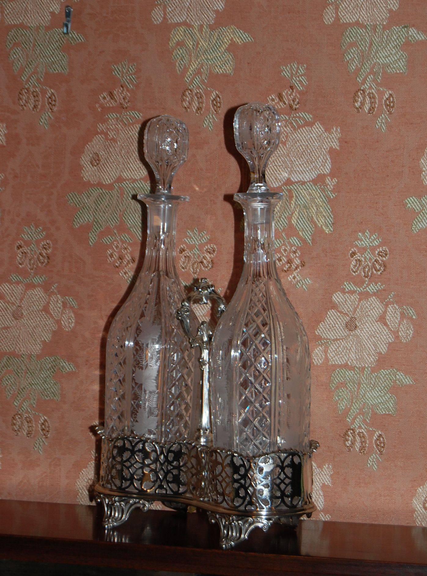 Silver plated Tantalus with two cut-glass decanters with original stoppers, in a Classic English style, circa 1850. The decanters are quality cut-crystal with beautifully engraved decorations of grape leaves and vines.