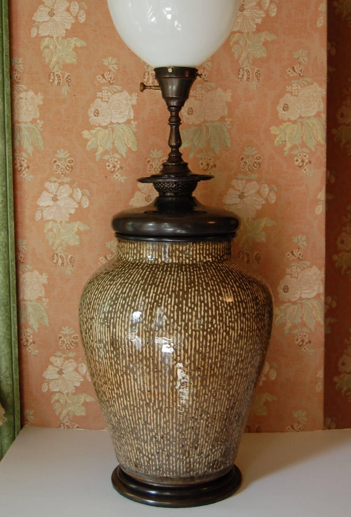 Wonderful large Asian, possibly Chinese or Korean urn wired as a lamp with original turn of the century base and fittings. Could have originally been an oil lamp. Olive and ecru colored strike' glaze. Just cleaned and rewired with a three-way