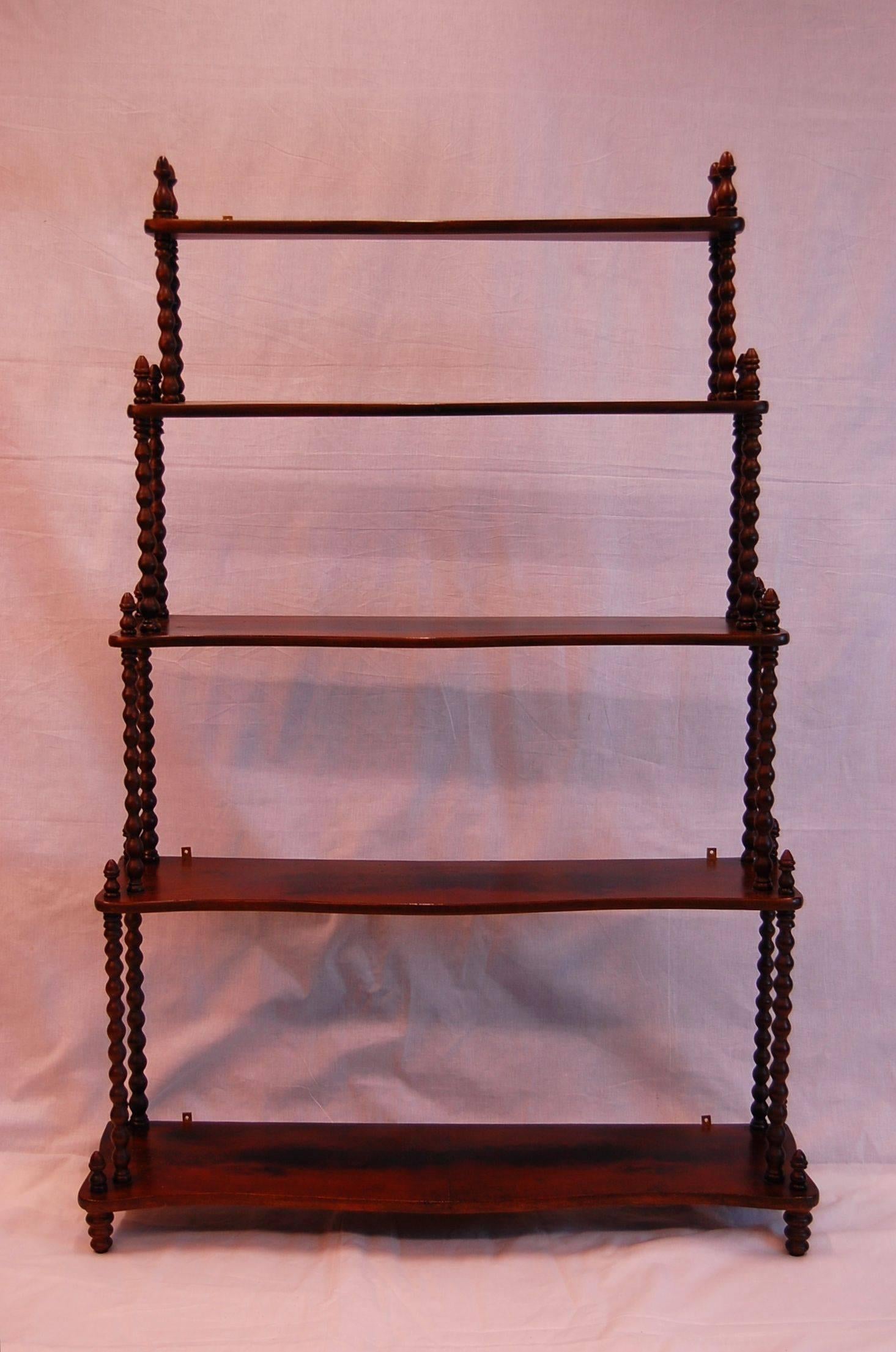 Mahogany five-tier wall-mounted shelf in excellent condition. Measures: The depths of each shelf center is: 5.5, 6.25, 7.25, 8.25, 9.25. The space between each shelf starting at the top is: 7 5/8; 10; 12 & 14 inches. Excellent condition with 3 sets