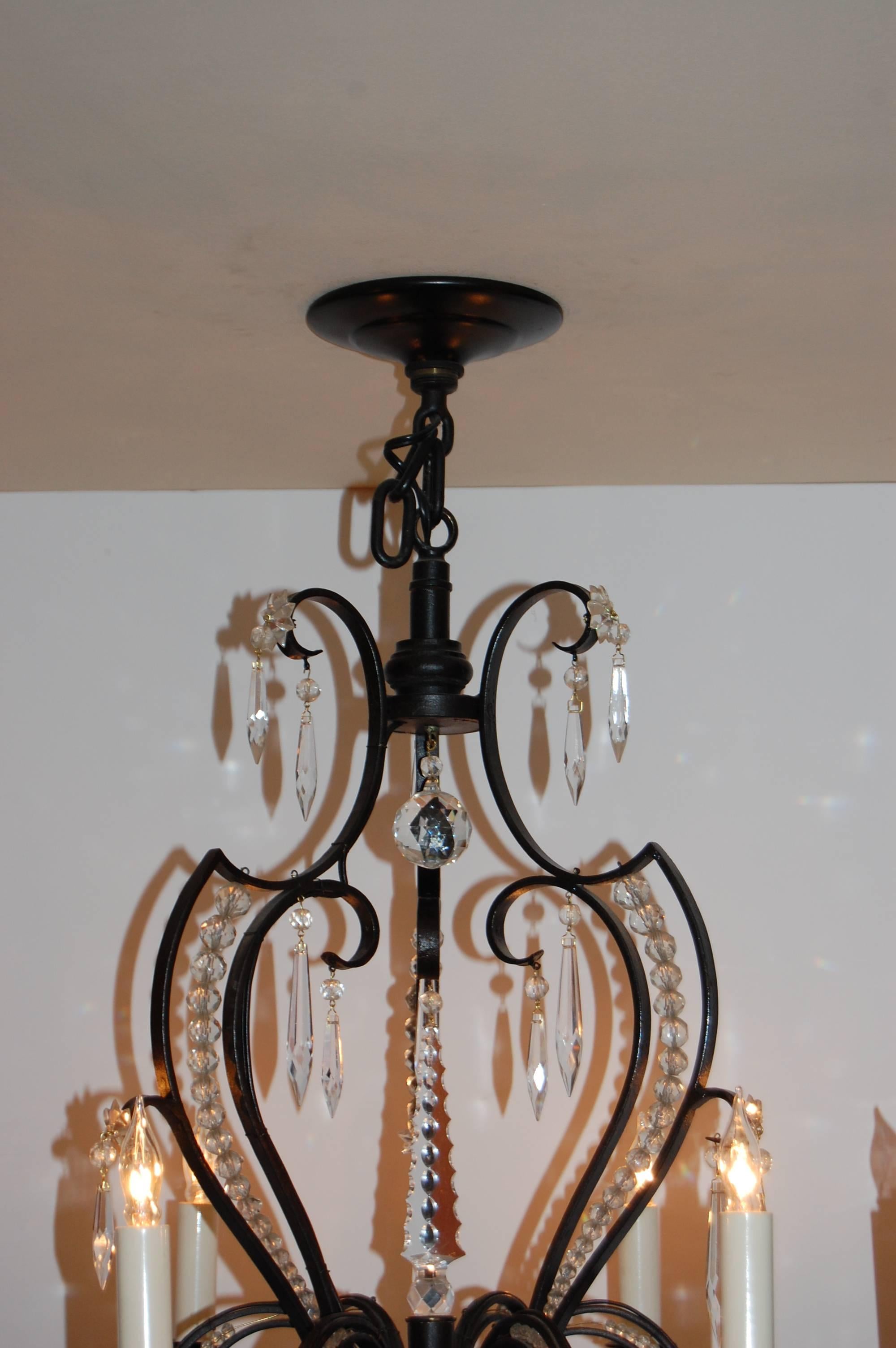 Iron six-light chandelier in a black painted finish with crystal drops and chains of cut crystal beads, recently cleaned and rewired. Measure: The length is 25 inches and does not include approximately 6 inches of chain, 24 inches in diameter.