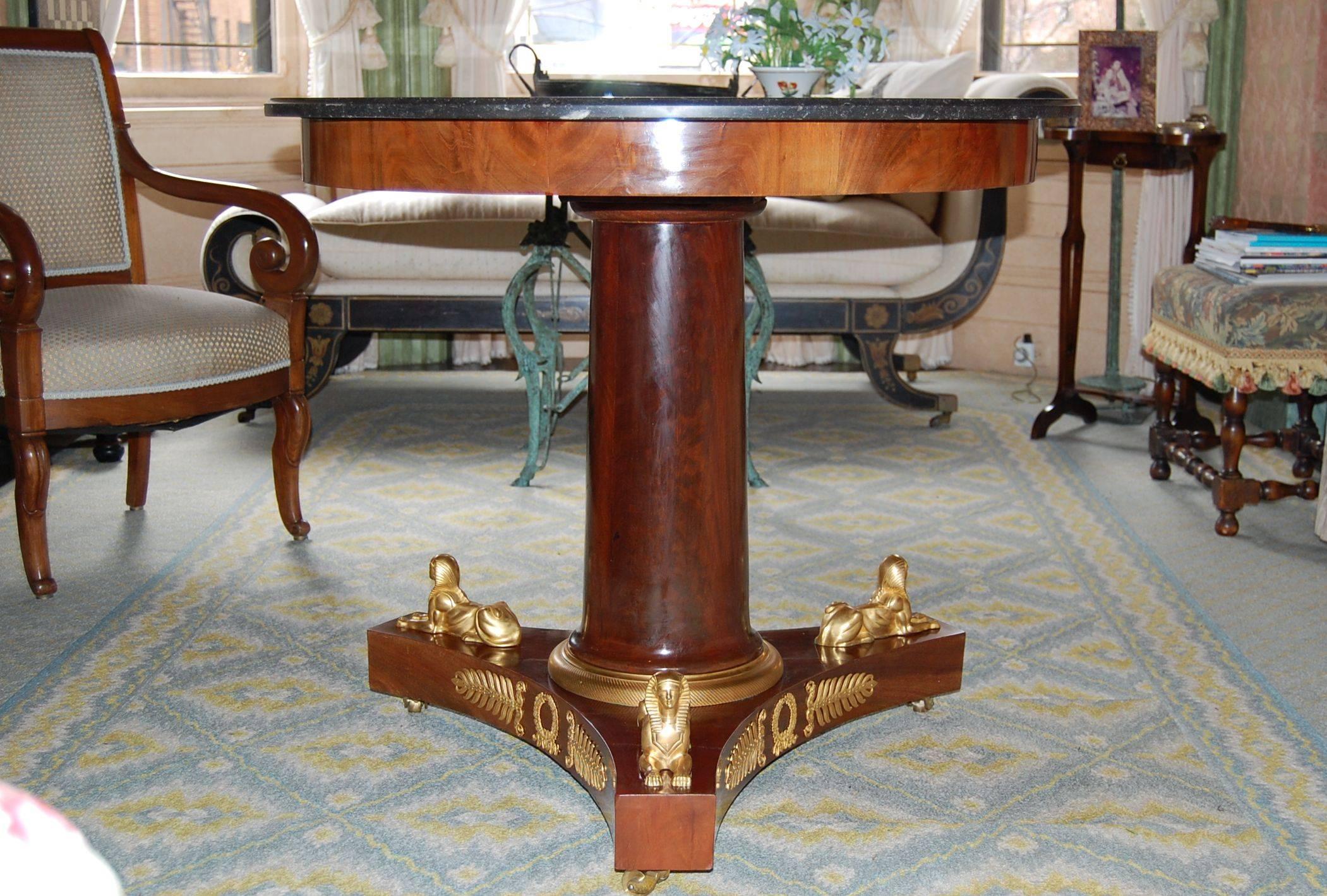 A mahogany French Empire gueridon with original fossil marble top, above a cylindrical column, to a plate form base with a circular ormolu ring and original ormolu mounts. Base has three Sphinx and ormolu as well.