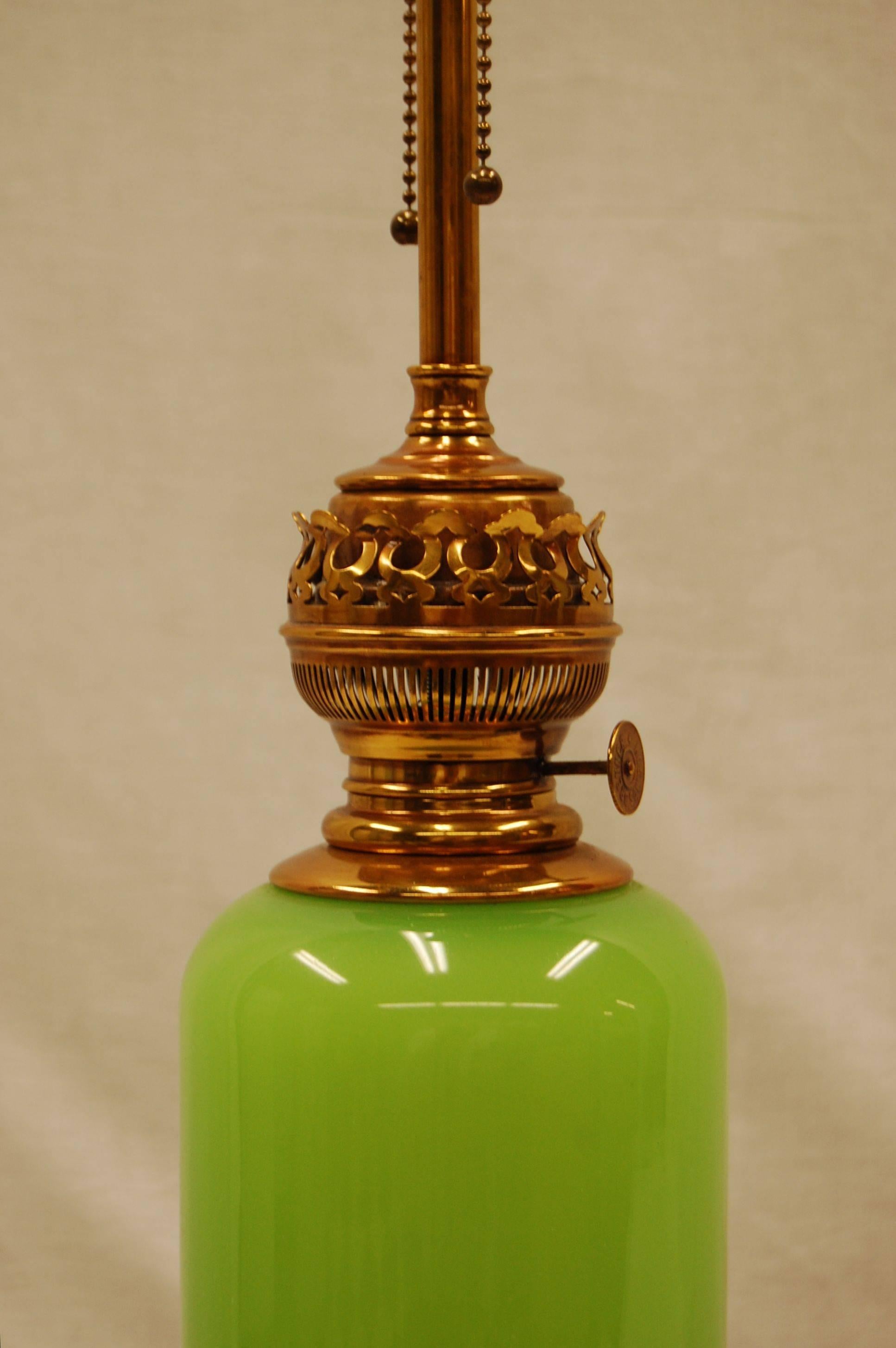 This bright green glass lamp with brass fittings is of a very fine quality. The height to the top of the brass burner is 18 1/2 inches.