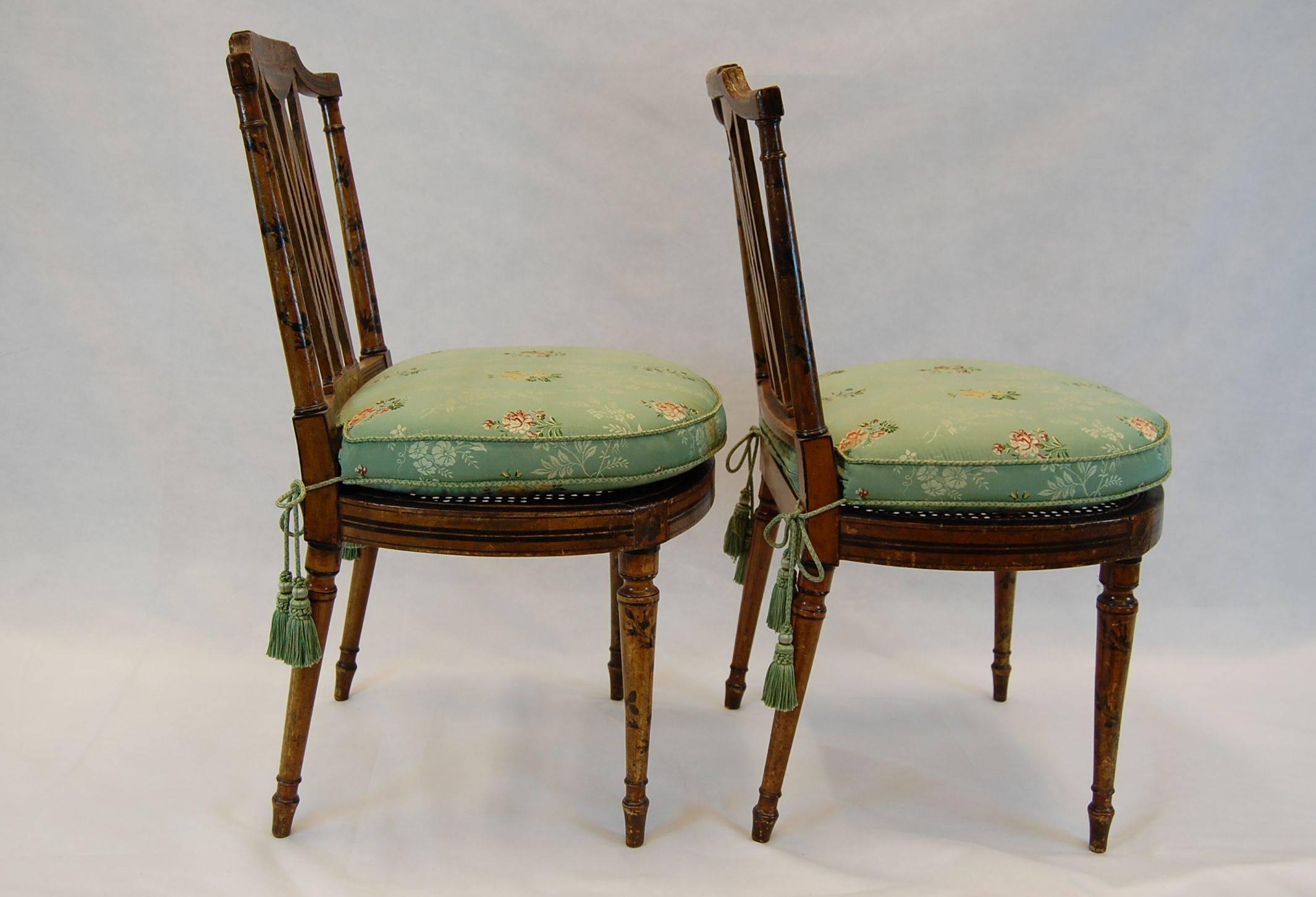 Pair of English Hepplewhite-style side chairs with caned seats and pads. The fabric is silk brocade by Clarence House with silk chair tie tassels. The inserts are down-filled. Beautifully decorated frames in the style of Angelica Kauffman, late