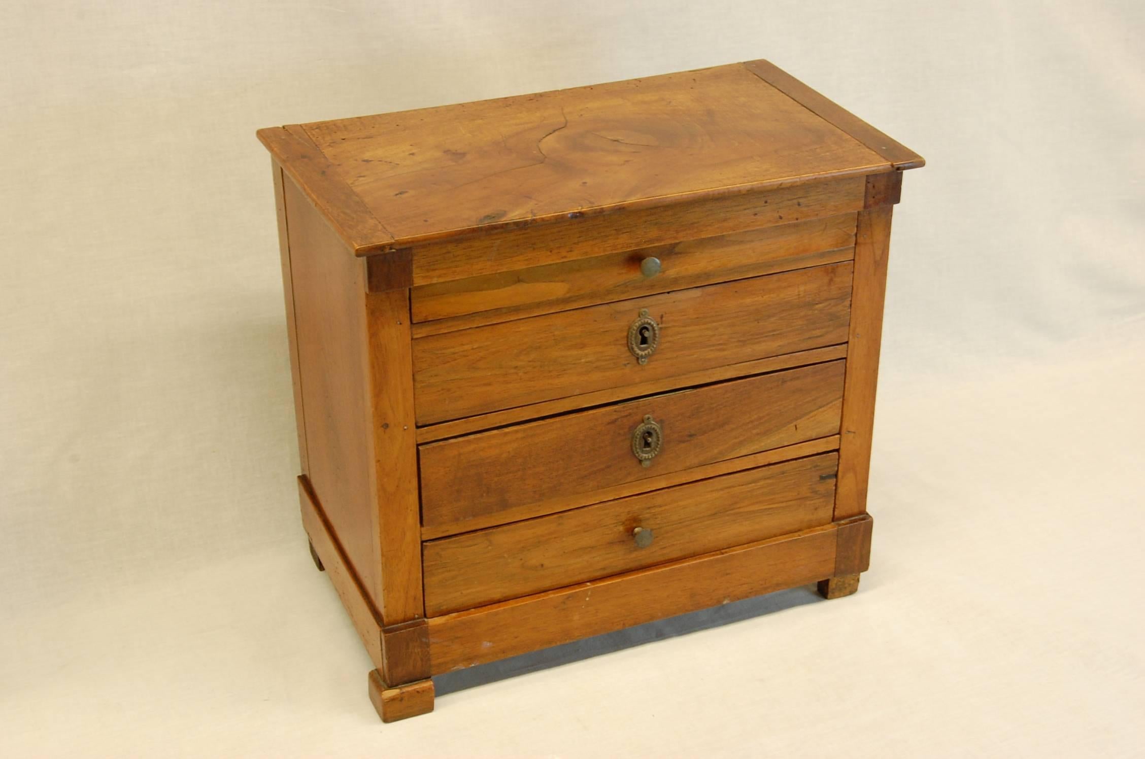 Wonderful miniature chest with four drawers, two of the drawers have locks but no keys. Missing the right front foot trim, otherwise good condition.