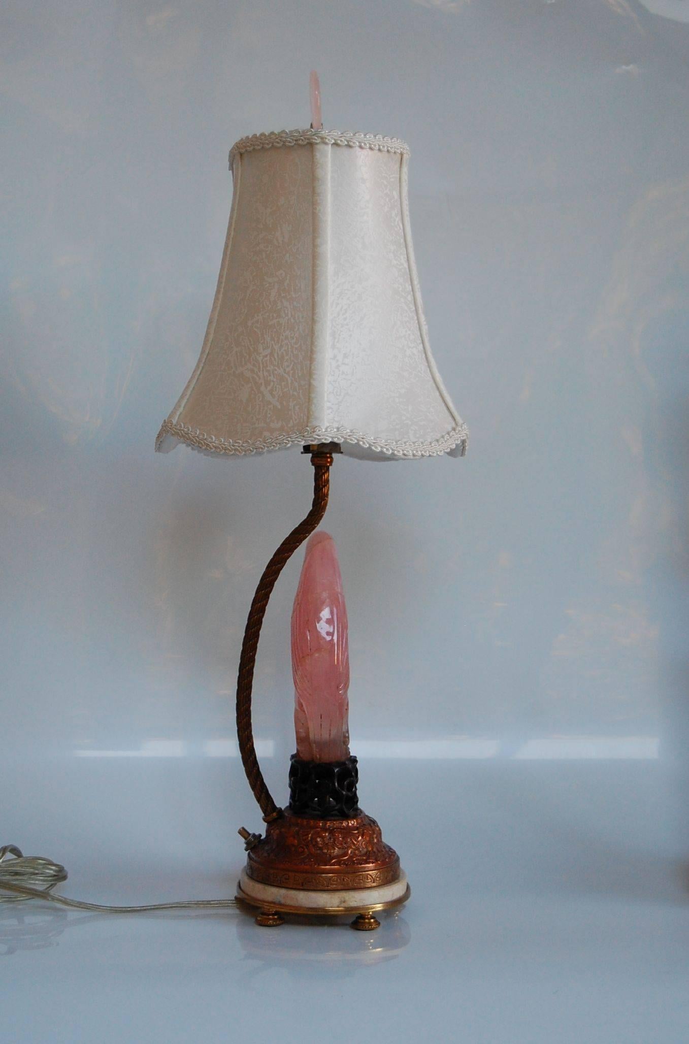 Pair of carved rose quartz dressing table lamps with birds, with original custom scalloped shades newly covered in a silk pongee. Sitting atop the original oval copper repousse' and brass bases with pink marble and hand-carved rosewood plinth. It is