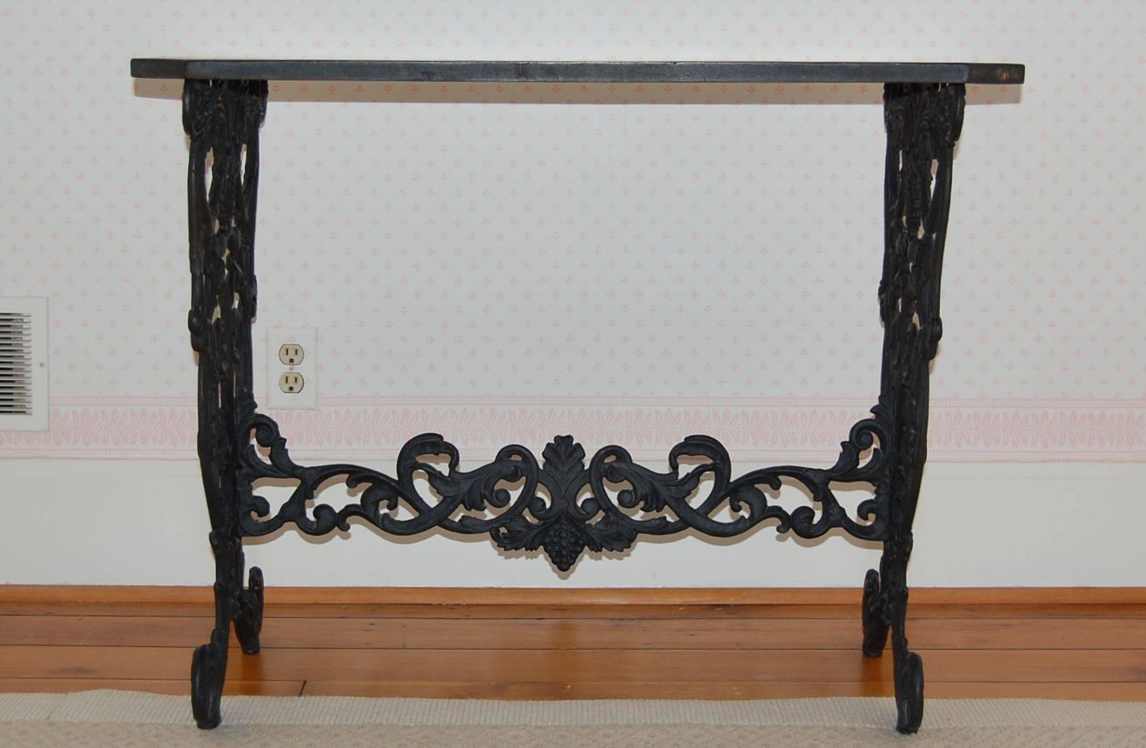 Elaborate cast iron table base with the original cast iron top in black painted finish. The base consists of wonderful upturned eagles heads, grapes and other birds.
