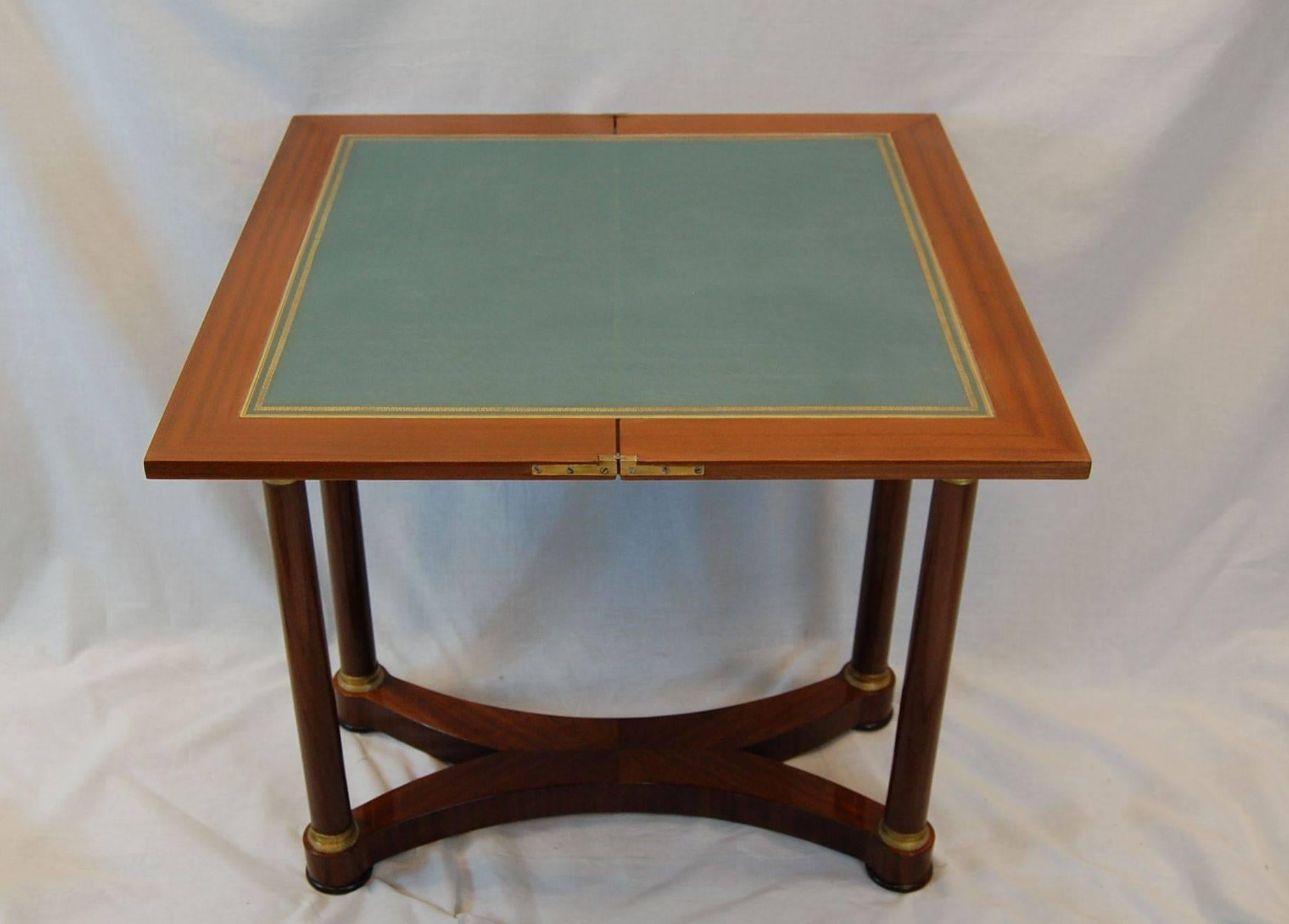 Beautiful mahogany flip-top games table with bright gold doré bronze ormolu top and bottom of the columns. Newer blue leather insert with gold tooled line. The top when in the open position is 30.5