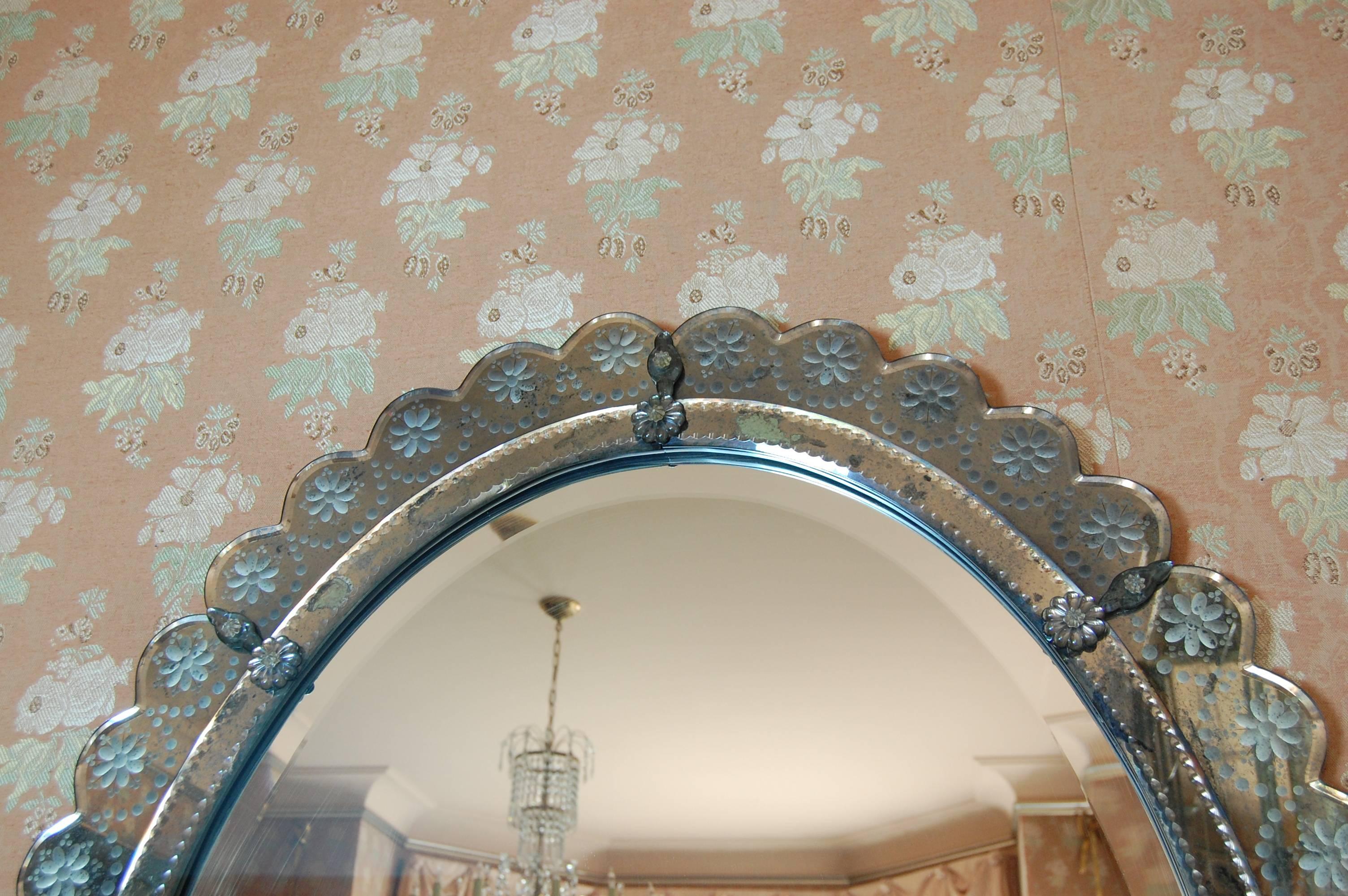 Exquisite oval mirror 4' tall and 3' wide, with a 1 1/8 inch wide bevel on the center piece of glass. The border is all wheel-cut in a floral design, on blue gray glass. There is minimal marking on the reverse side of the mirror, as shown in the