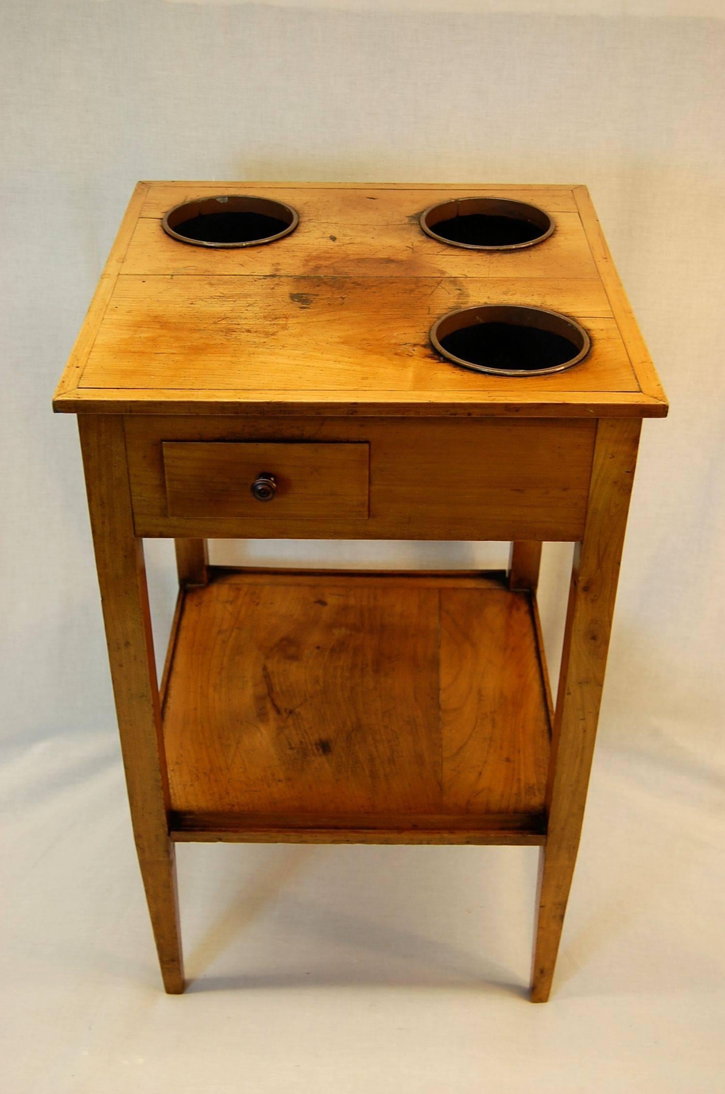 A Rafraichissoir Table in Fruitwood with three wine buckets, French in origin, with straight, tapered legs and one drawer. The buckets are newer painted and galvanized bowls. 