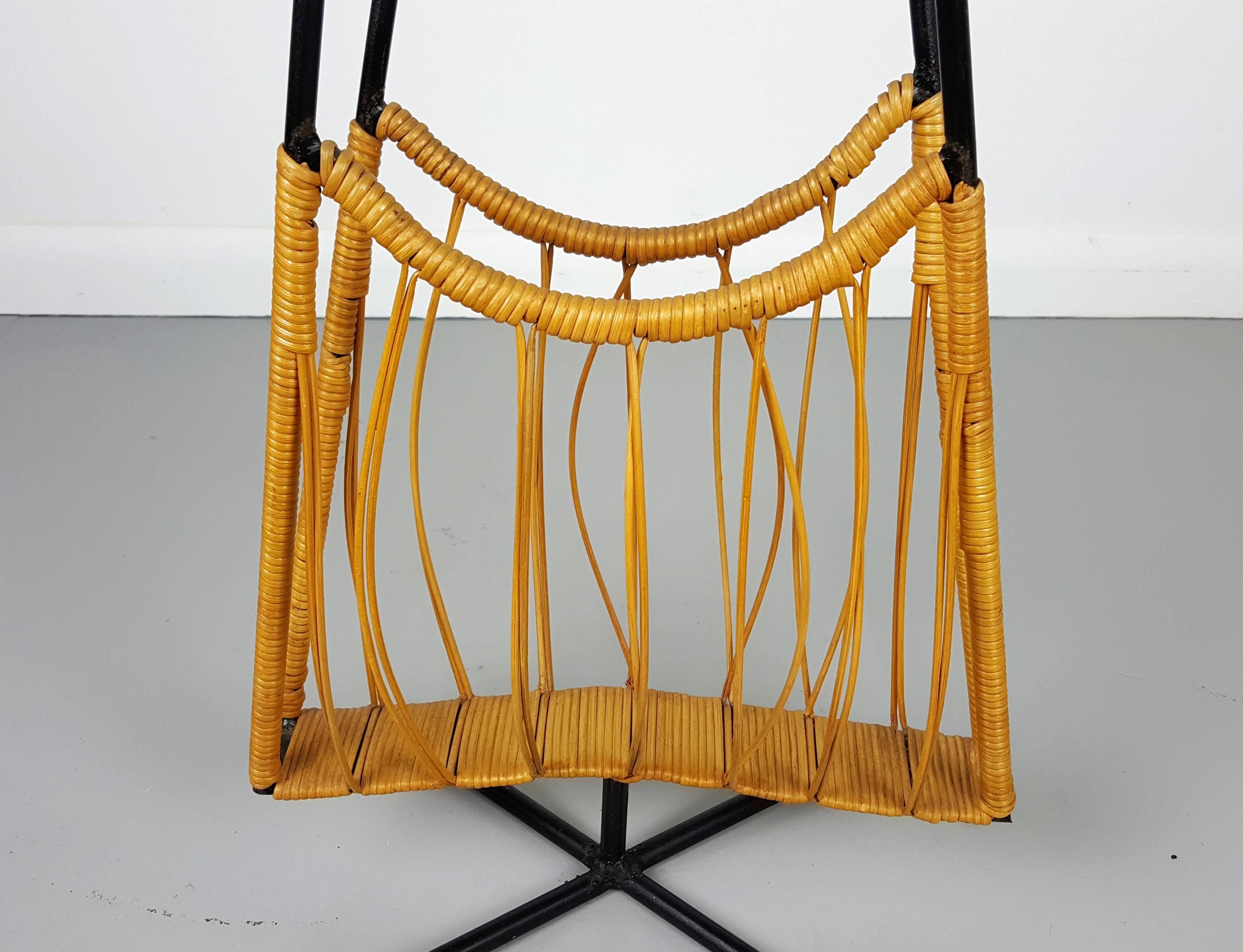 Wonderful and rare sculptural atomic age magazine rack in wicker and iron. Lovely example of California modernism. This piece has a small footprint, but the overcalled height creates big design impact.
Piece is in excellent vintage condition and