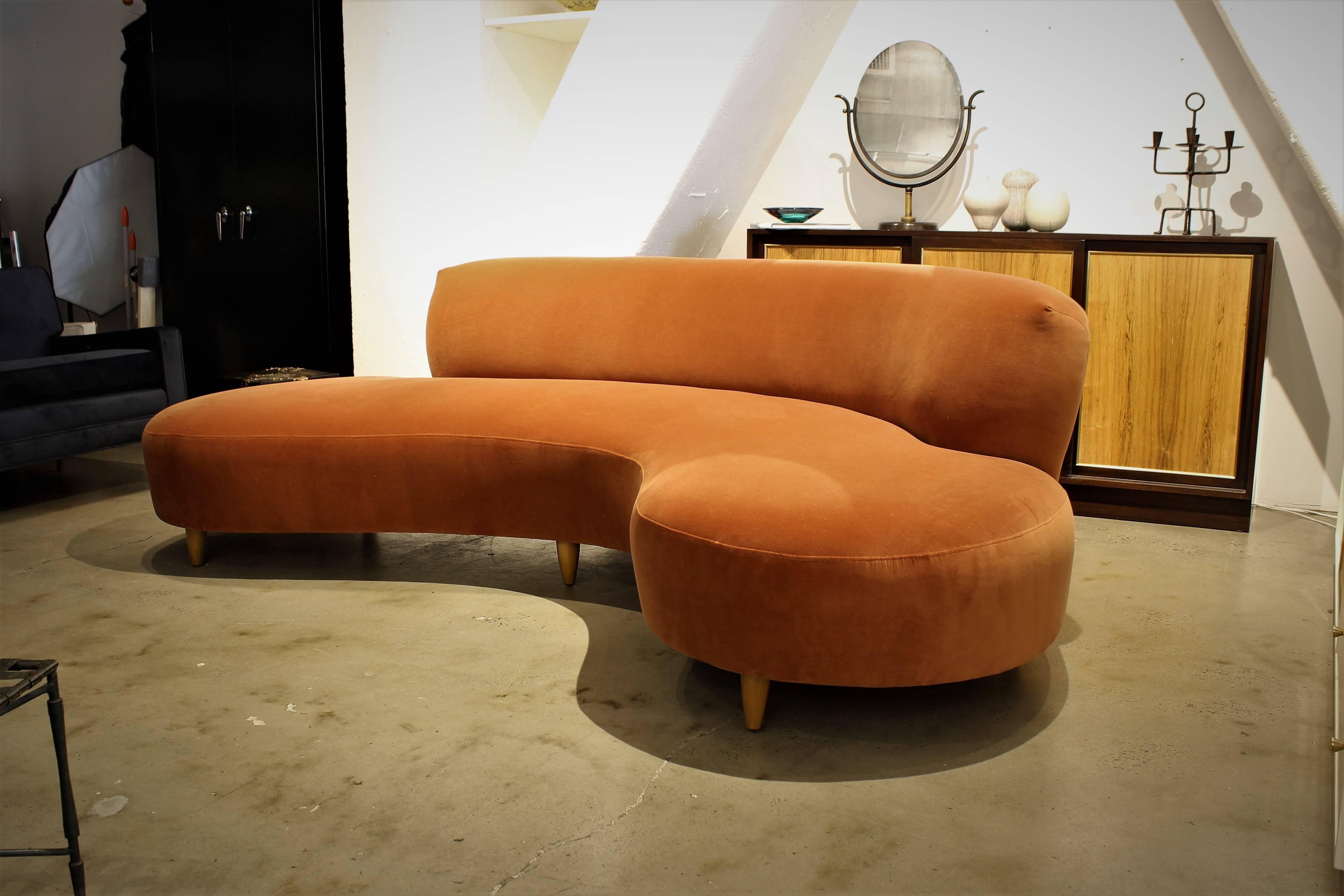 Stunning and sculptural sofa by Vladimir Kagan. This is an early version of this design. Often called the cloud, serpentine, or kidney sofa. This piece has become an icon of modern furniture. Newly upholstered in an apricot velvet. The tapered legs