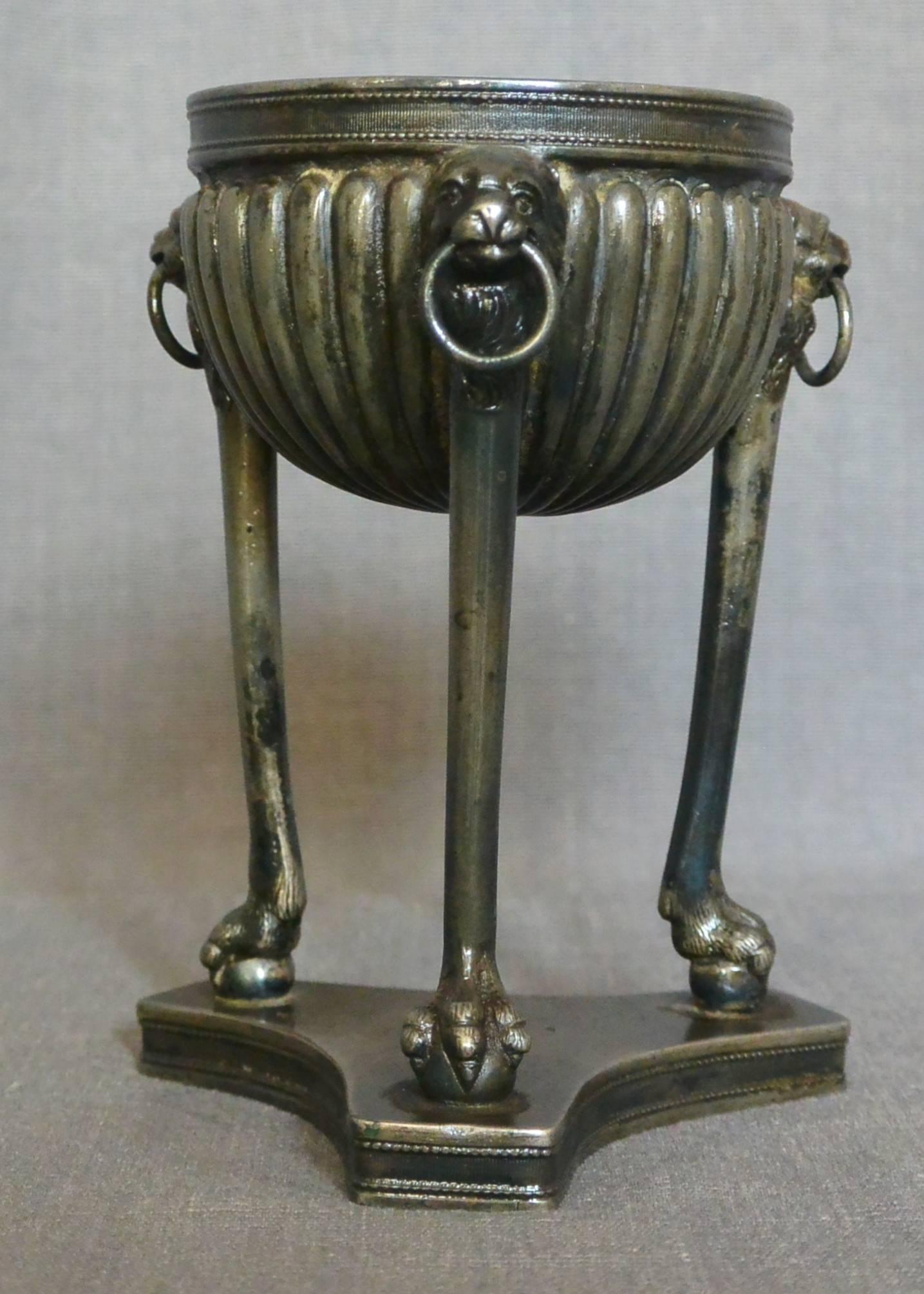 Grand Tour Neapolitan Tripod Oil Lamp. Bronze patinated metal oil lamp of tripod form with lion head masks with rings, supported by lion monopedia on ball terminals on conforming base, Italy, circa 1820.
Dimension: 4.75
