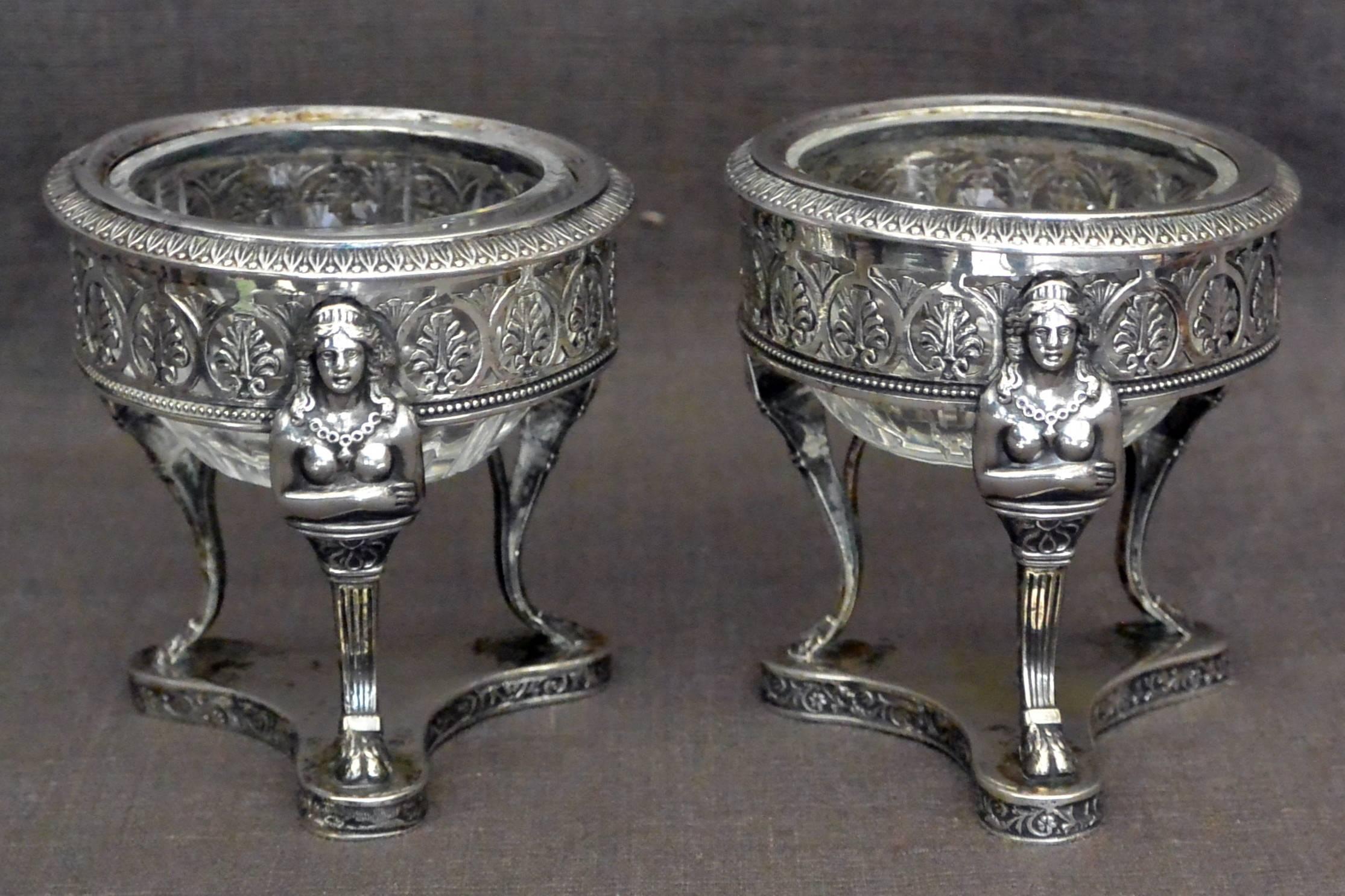 Pair Italian neoclassical silver salts with hermes. Pair of antique neoclassical sterling silver salt stands of Empire tripod form with pierced anthemion band supported by Hermès on hoof feet above conforming base; with associated crystal liners.