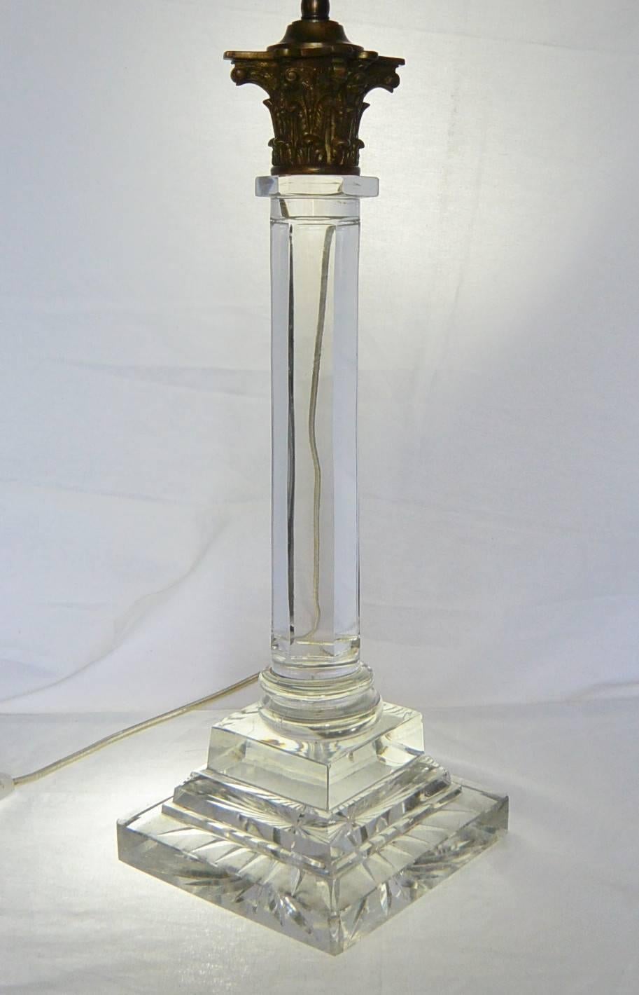 English crystal column lamp.  Antique crystal Corinthian column lamp with fine heavy brass capital above faceted column on stepped pedestal base. Newly electrified with silk cord and switch. England, mid-19th century.
Dimension: 6.25
