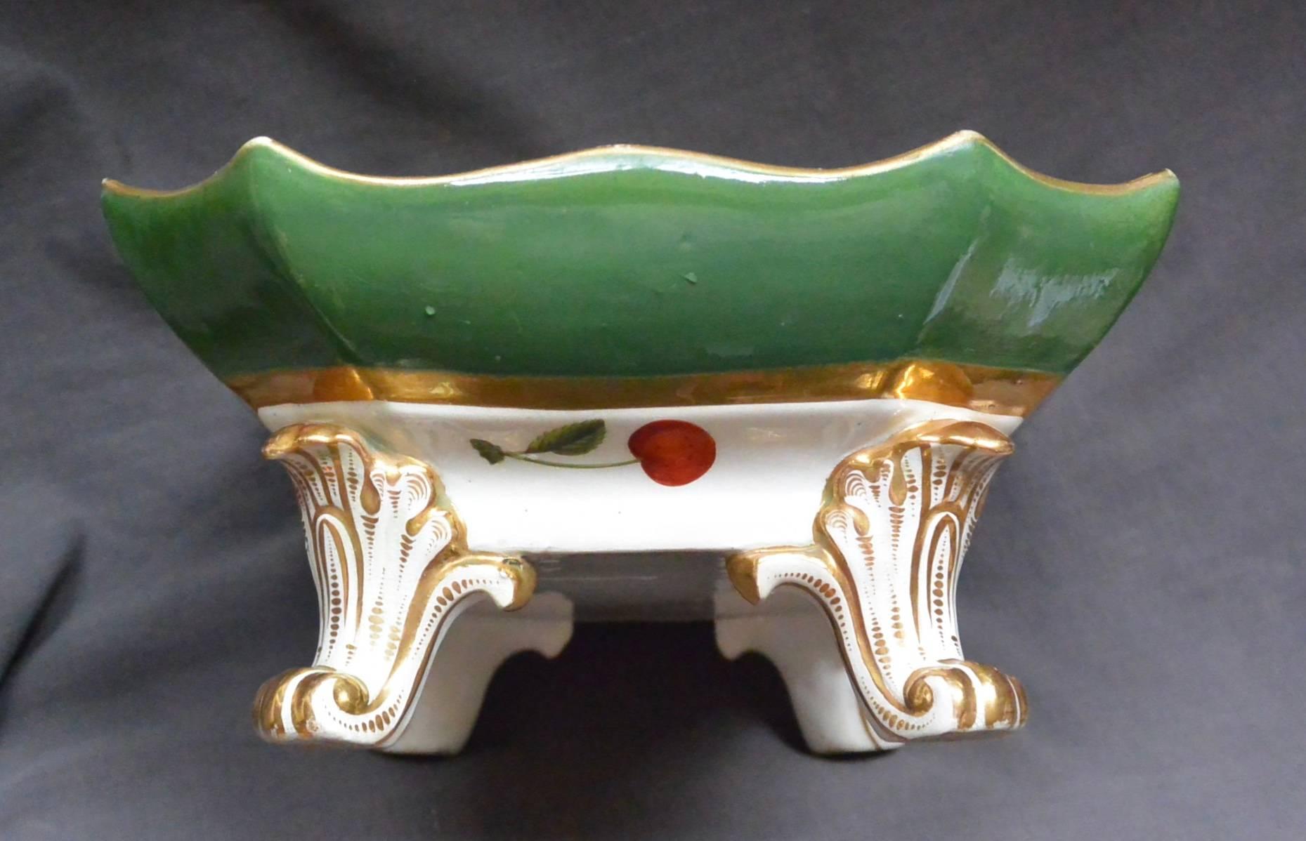 Purple and green gilt porcelain flower and fruit compote. Eight sided and shaped botanical themed strikingly painted green, purple and gold serving dish with green band and gilt borders, centering on painted purple and yellow fruit and pansies, all