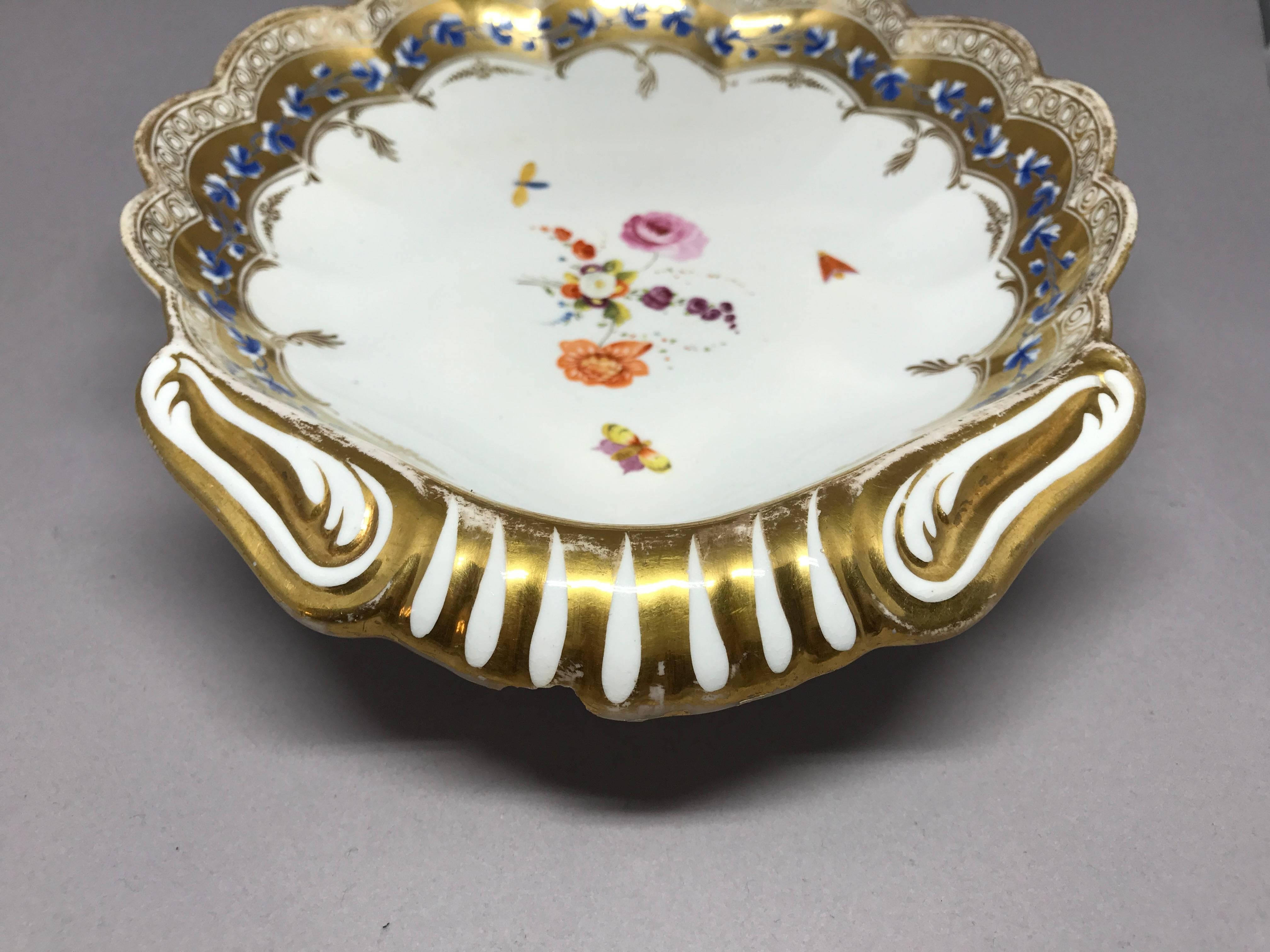 English gilt painted shell form serving dish. Lobed shell shaped sweetmeat dish/plate with gold and blue band centering on small flowers and butterflies. Underglaze blue 