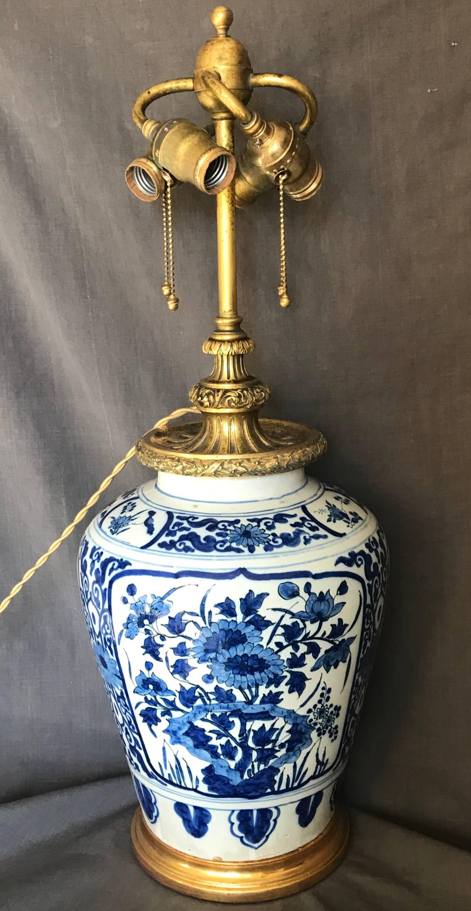 Dutch Delft blue and white lamp. Beautiful large Delft faience vase mounted as a lamp with bold floral decoration and borders with spectacular later Calder gilt bronze four-light mount on custom gilt water base. Newly electrified with gold silk