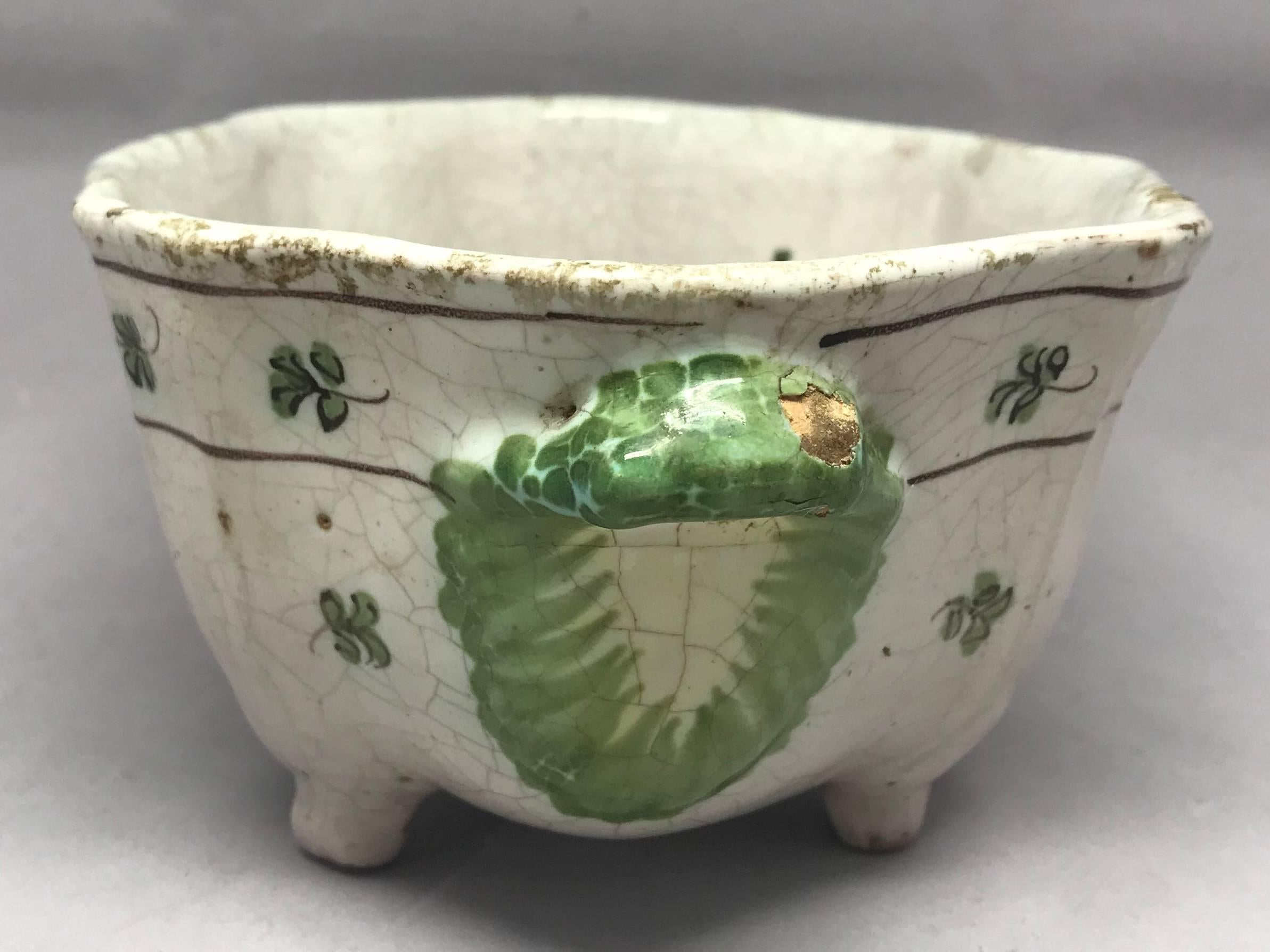 Cerreto majolica shaped bird bowl. A glazed faience majolica shaped and footed bowl with green, yellow and blue accents featuring a bird amongst foliage to both sides with green leaf handles and a floral banded border from the Cerreto Sannita