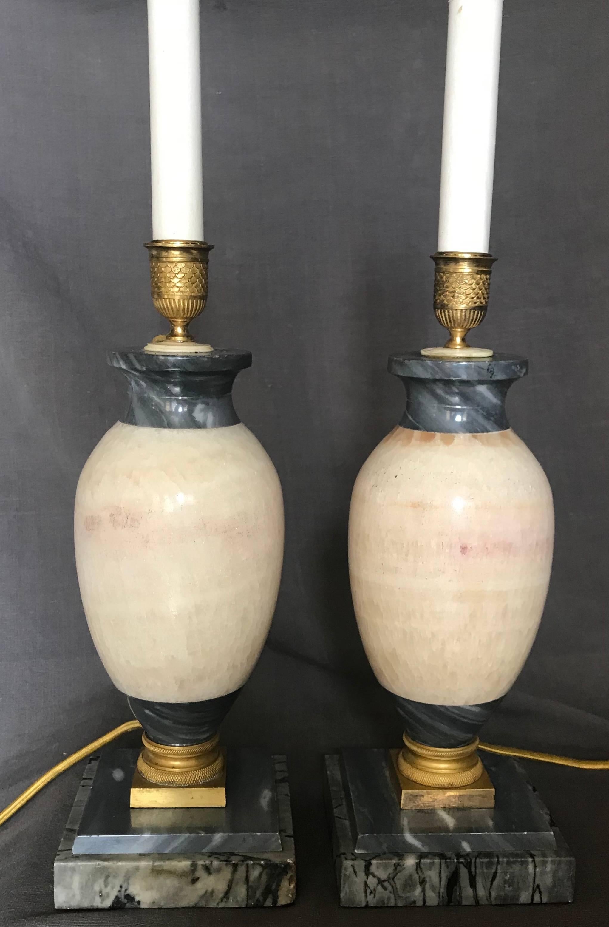 Pair of blue John marble lamps. Continental blue John table lamps of baluster form with grey-beige and purple accents with grey marble and chased gilt bronze mounts. Newly re-wired with candelabra base and silk cords with switches, Europe, early