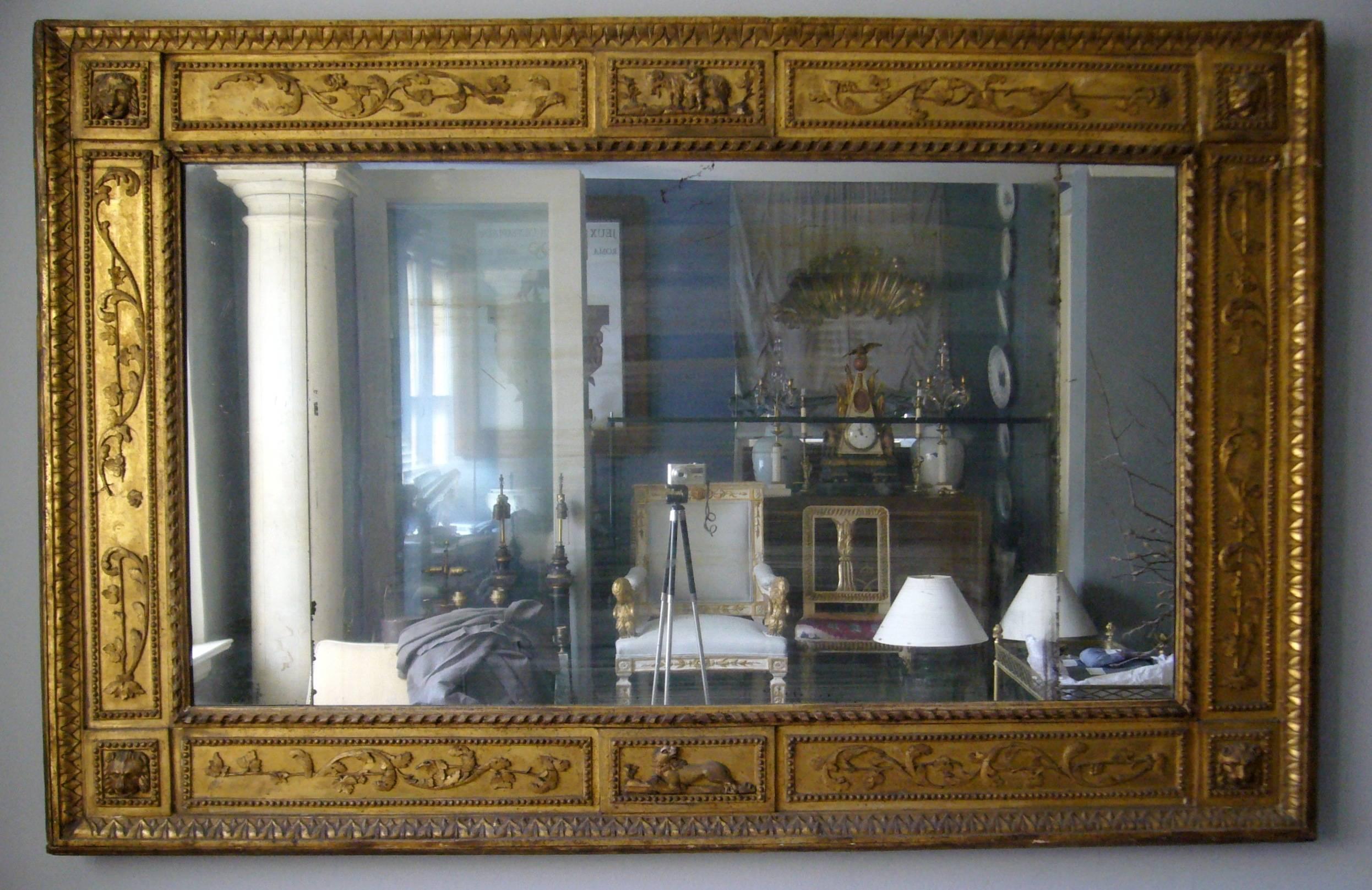 Specchio neoclassico italiano in legno dorato.  Specchio d'epoca intagliato e dorato con contorno di acanto a volute, bordo esterno a punta di foglia con maschere di leoni angolari e bordo interno con nastro che circonda la lastra di vetro
