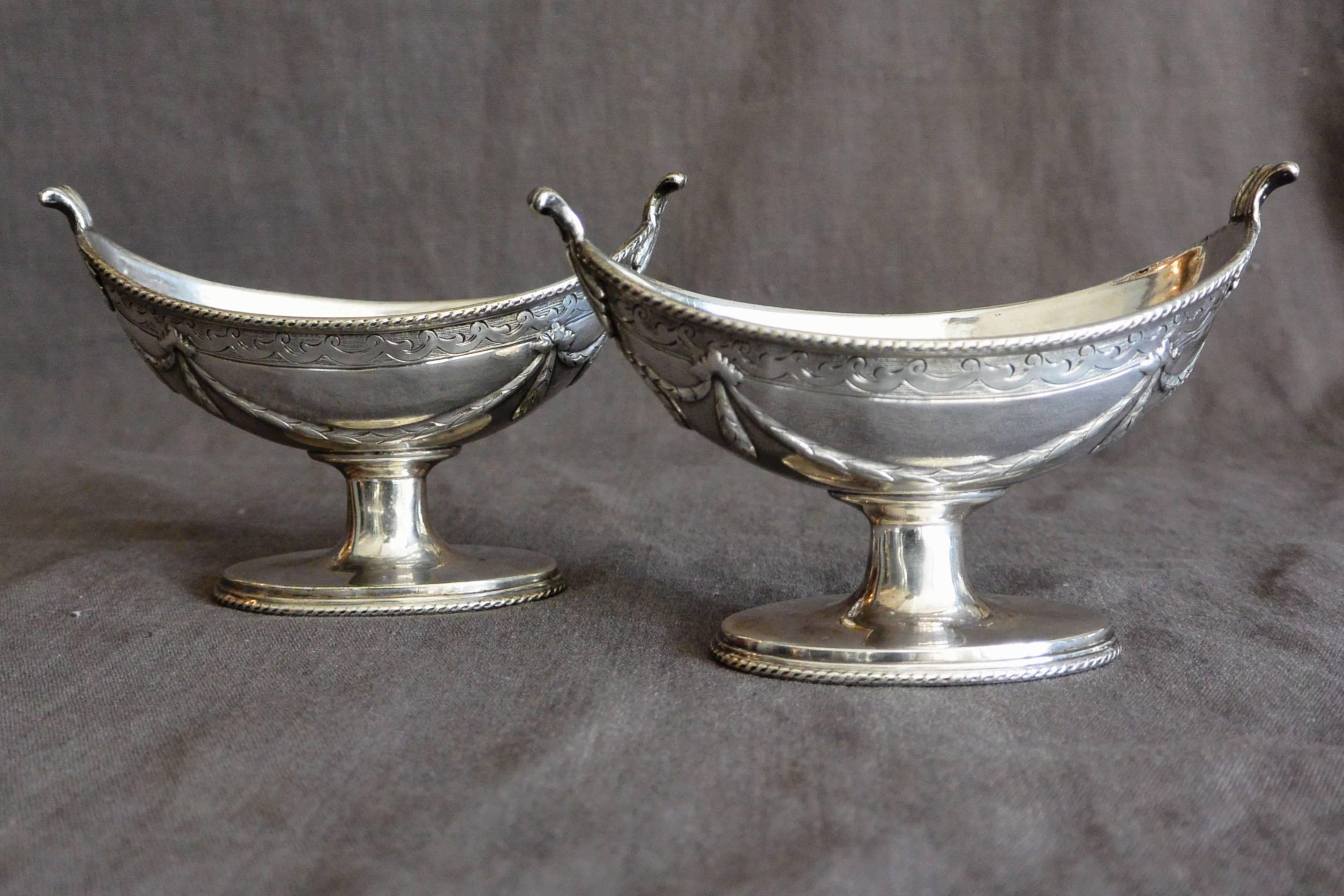 Pair English sterling silver bateau shaped salt cellars with incised roping detail at rim and base with swags and wreathing on oval pedestals. English hallmarks JAS DIXON & SONS Sheffield. Stamped PNS,#79
Dimension: 4.75