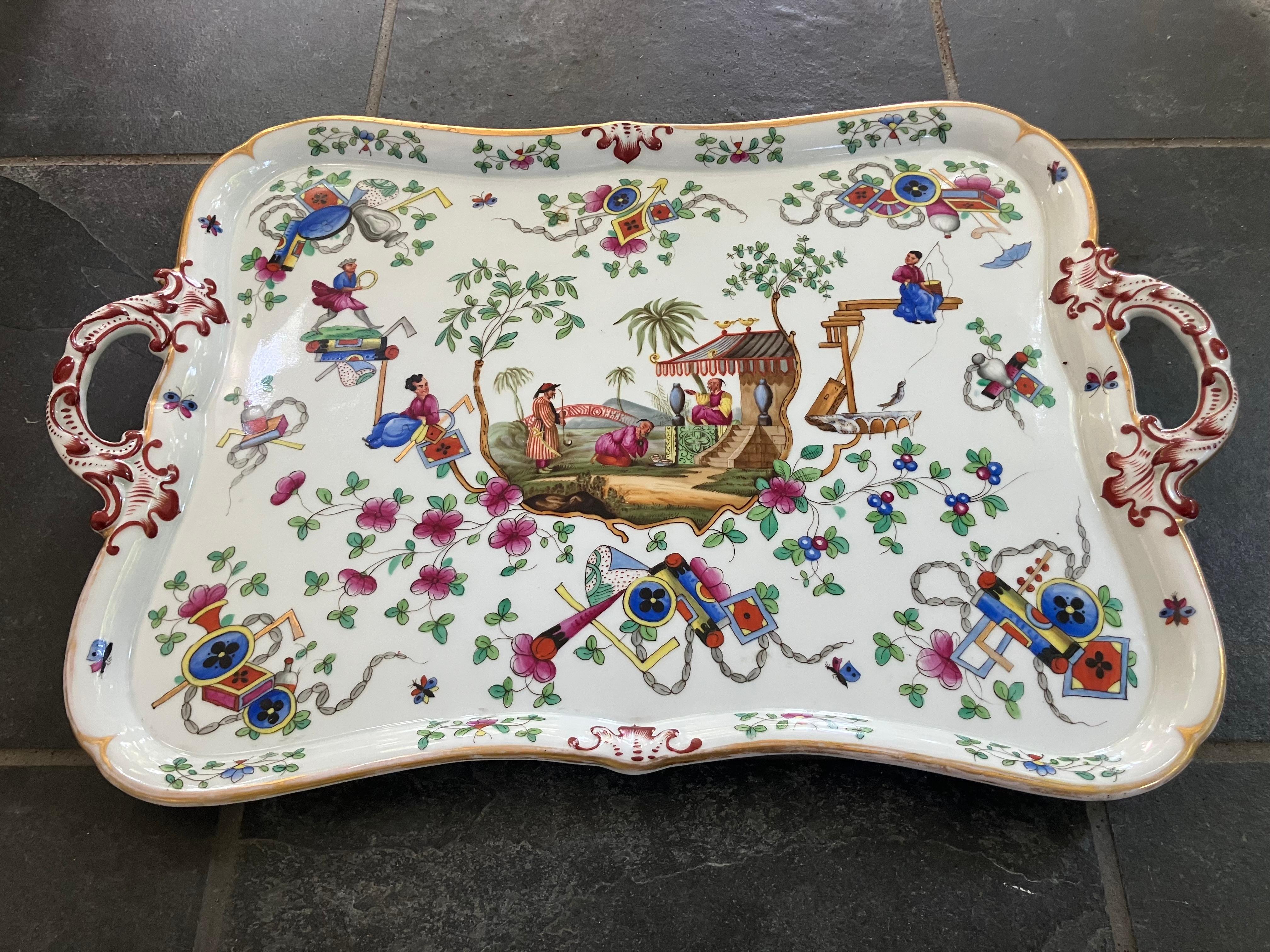 Kontinentale Chinoiserie-Tablett-Platte. Magentafarbenes, blaues, grünes, braunrotes und vergoldetes Tablett in Form einer Kartusche mit Griffen im Louis-XIV-Stil; handbemalt mit Chinoiserie-Landschaft, Gebäuden, Palmen und Figuren inmitten von