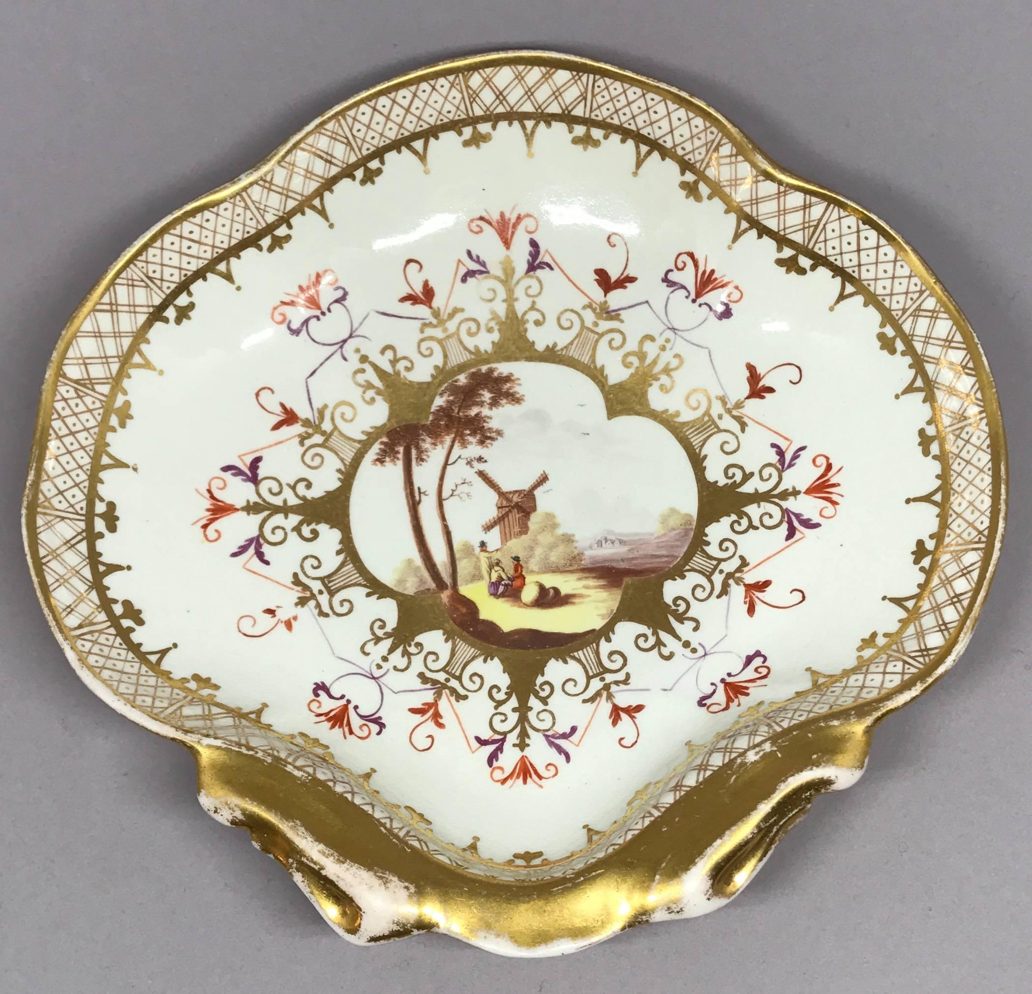 English iron red and gilt shell form serving dish after Meissen.  English chinoiserie shell form dish after Meissen. A rare coal port gilt porcelain sweetmeat plate decorated in the Meissen style with figures in a Dutch landscape painted in iron red