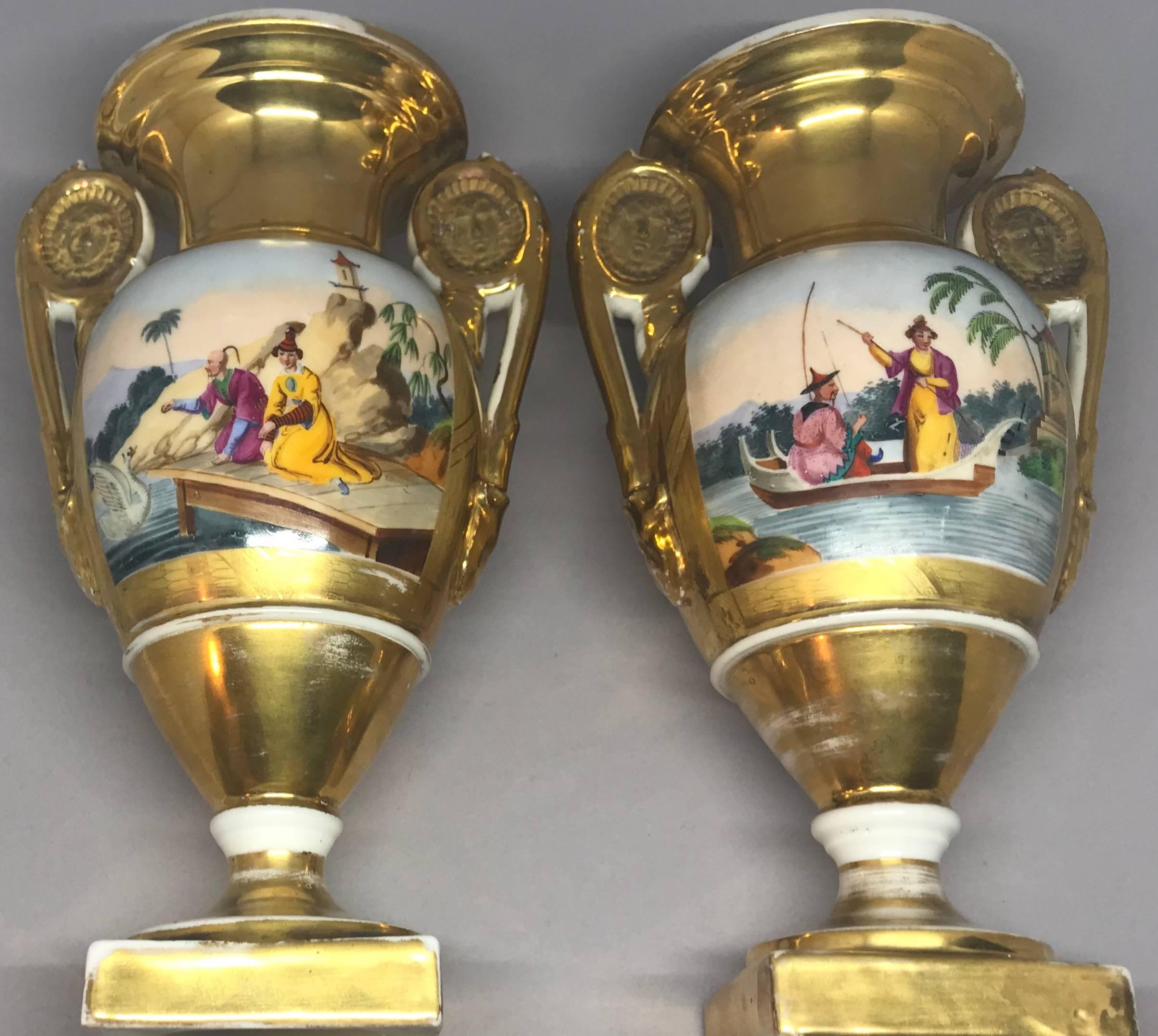 Coppia di vasi Impero dorati a cineserie. Coppia di vasi francesi dipinti a mano e dorati del periodo Impero con manici a maschera e bordi dorati incentrati su scene orientali riccamente colorate con figure e pagode in paesaggi in giallo, verde e