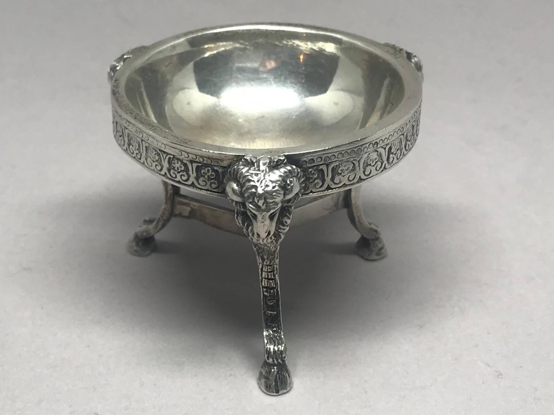 Pair hotel silver rams' head salts.  Pair neoclassical style tripod form silver plate salts with rams' heads terminating in hoof feet with stretcher to central ball finial all beneath circular basin, with stamps to stretcher.   American, circa