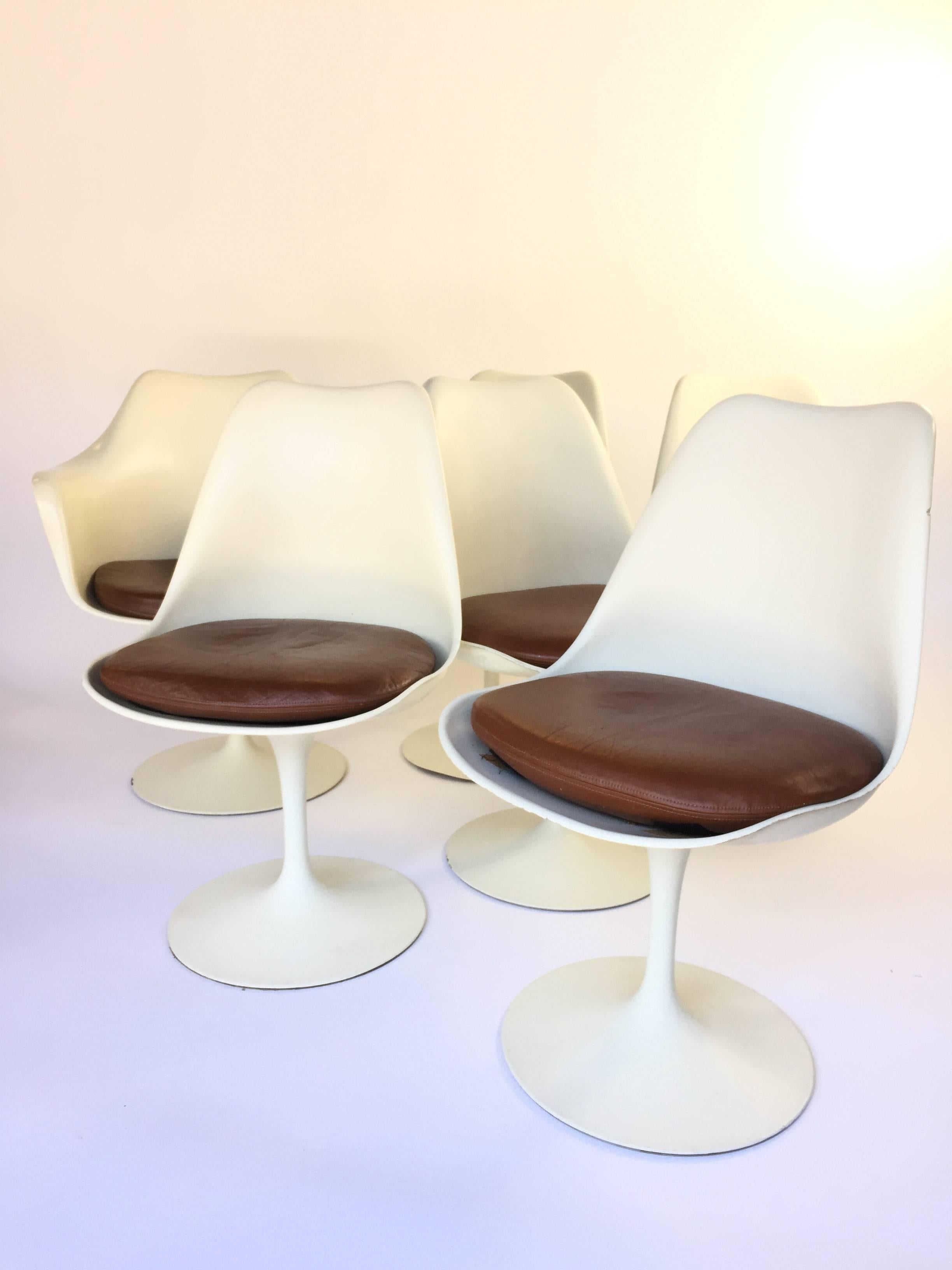 Five side chairs, one armchair. Eero Saarinen for Knoll Tulip chairs with original brown leather seats. Nice patina throughout. Not restored - original dings and dents plus supple worn leather. Very clean but not 