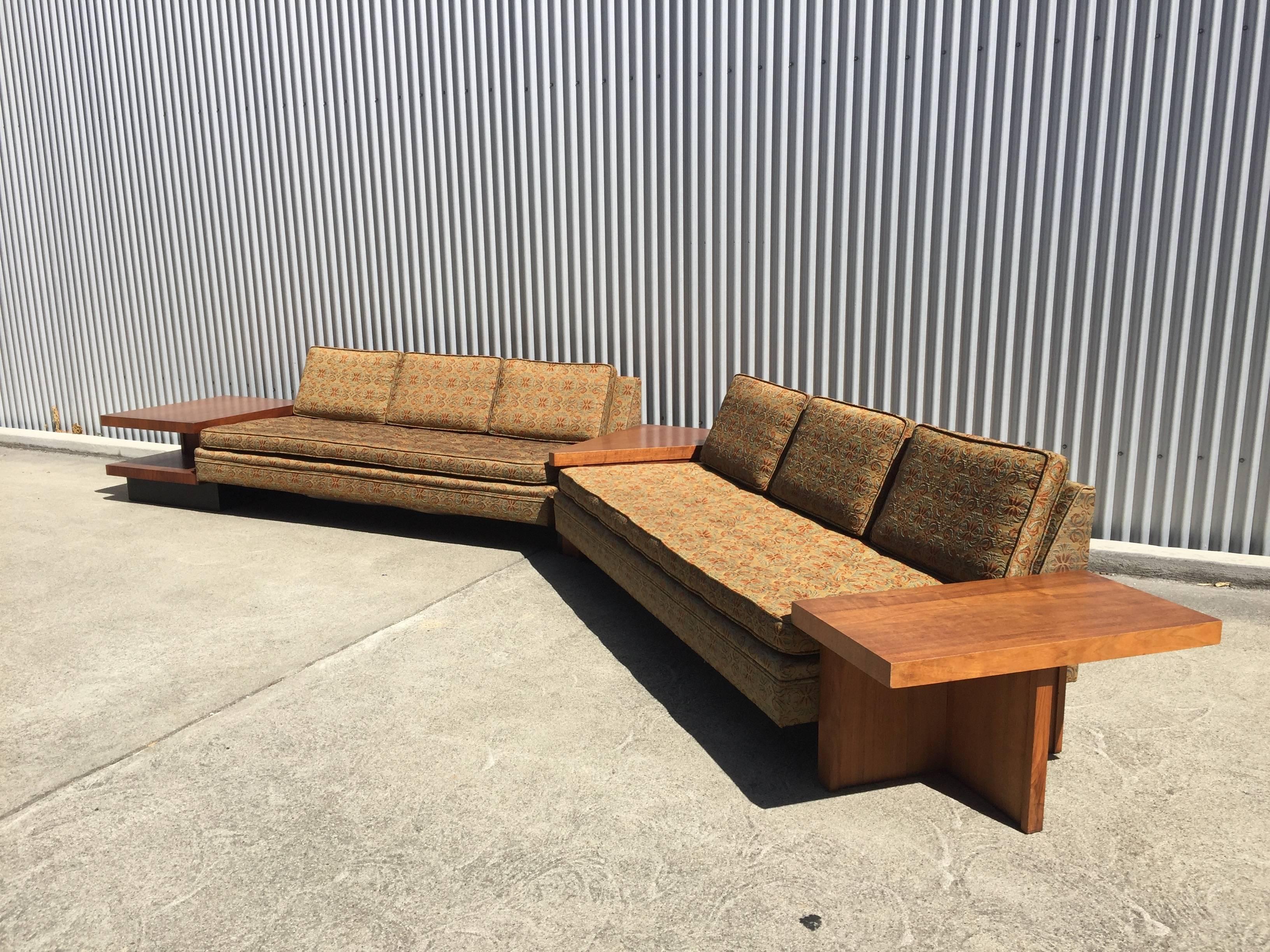 1960s MB designs sectional. Walnut and upholstery. Slim lined seating unit trimmed with walnut reveal around perimeter.

Enormous 16' dual sofa floating presence with an approximate 130 degree turning angle at centre. Embroidered fabric and foam