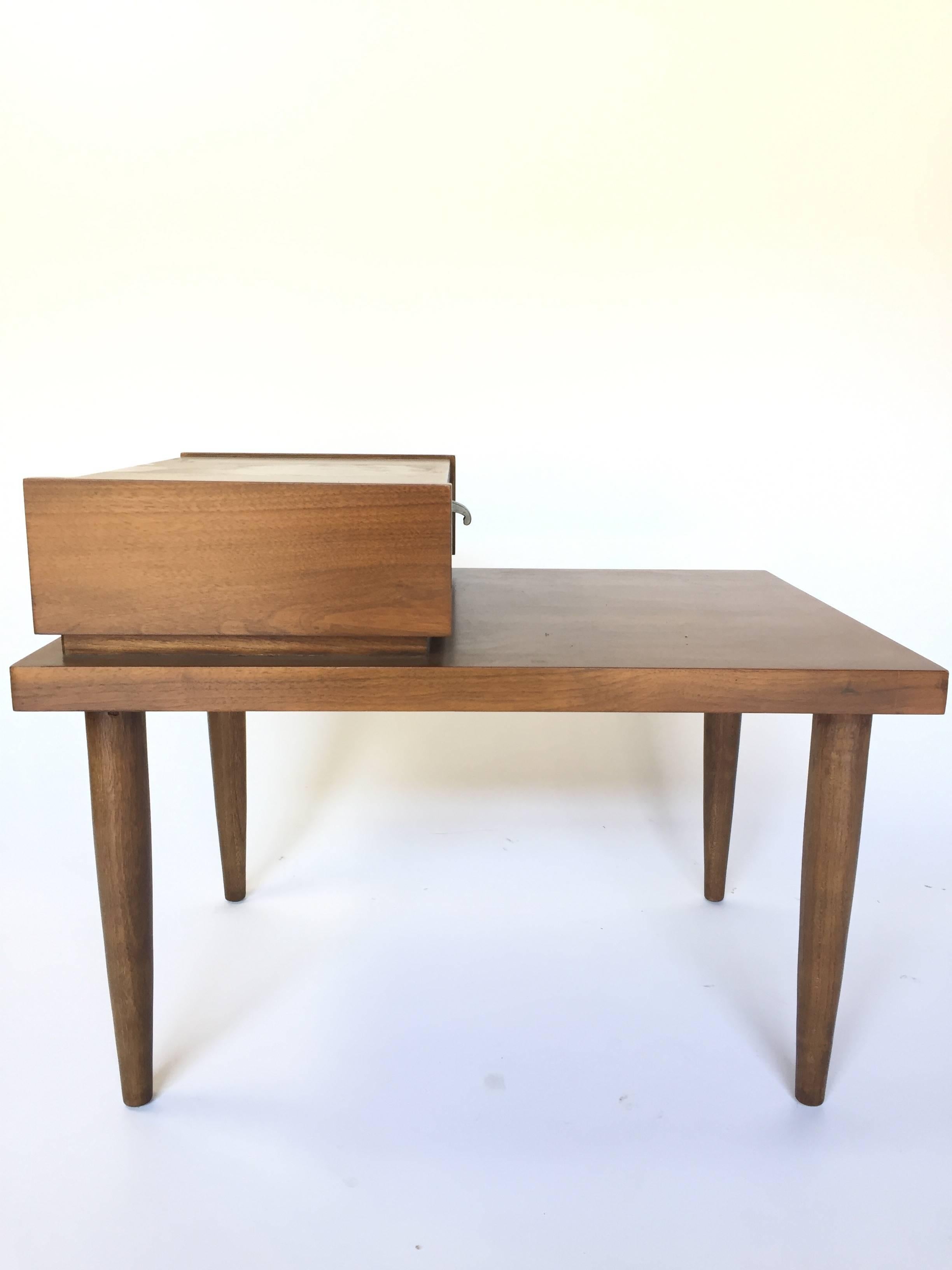 Pair of Mid-Century Modern nightstands / end tables by American of Martinsville. Features beautifully refinished walnut, an attractive step design, and a single drawer with George Nelson style J-pulls. Priced as a pair.