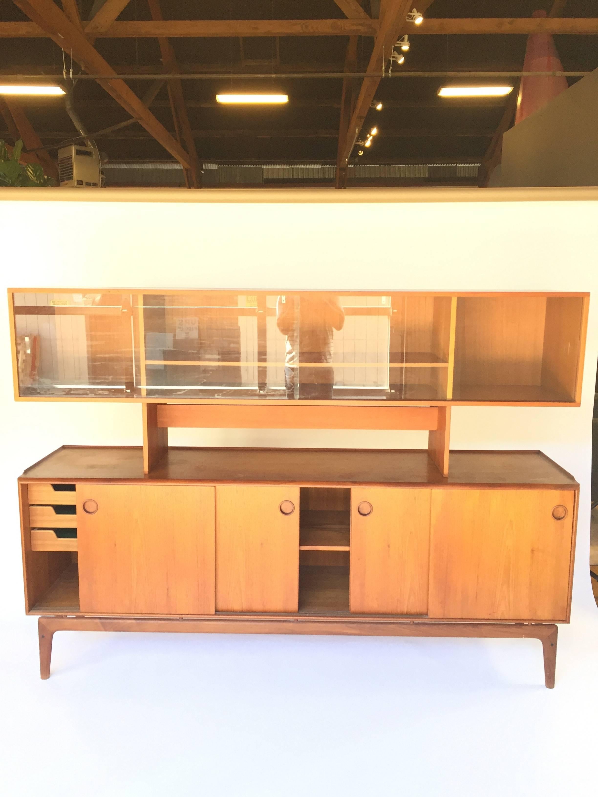 Stunning teak credenza designed by Jens Quistgaard and made in Denmark for Peter Løvig Nielsen. The top storage section of the credenza is removable and has sliding glass doors. Center and right sections of the credenza have an adjustable shelf,