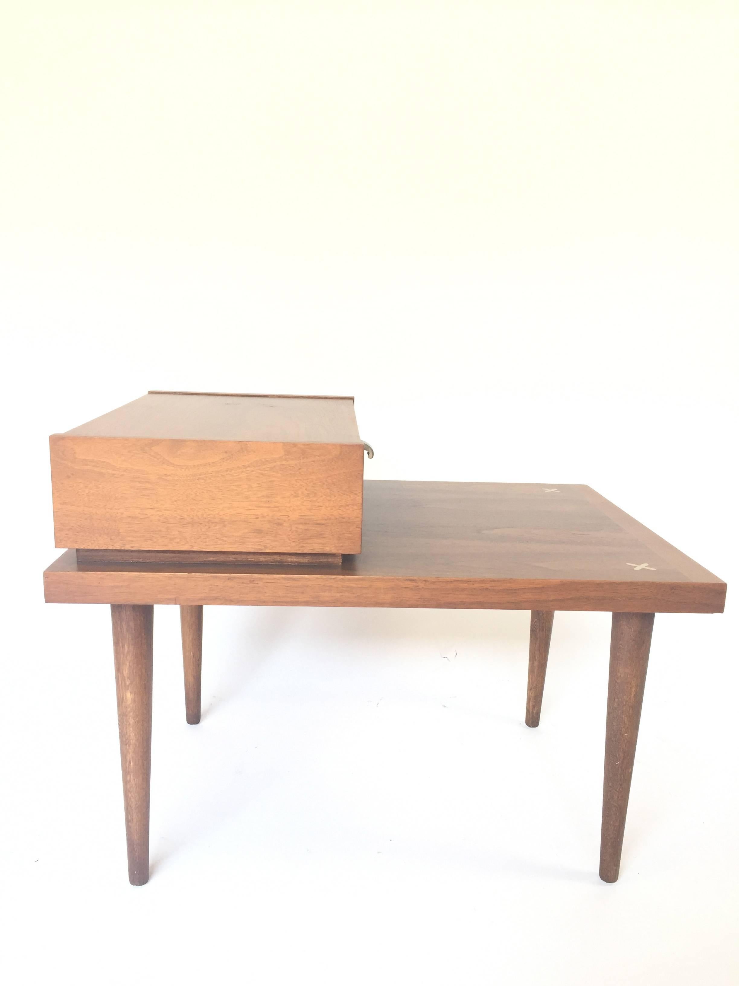Pair of Mid-Century Modern nightstands or end tables by American of Martinsville. Features beautifully refinished walnut, an attractive step design, and a single drawer with George Nelson style J-pulls. Unique X-shaped ornamental inlays in brushed