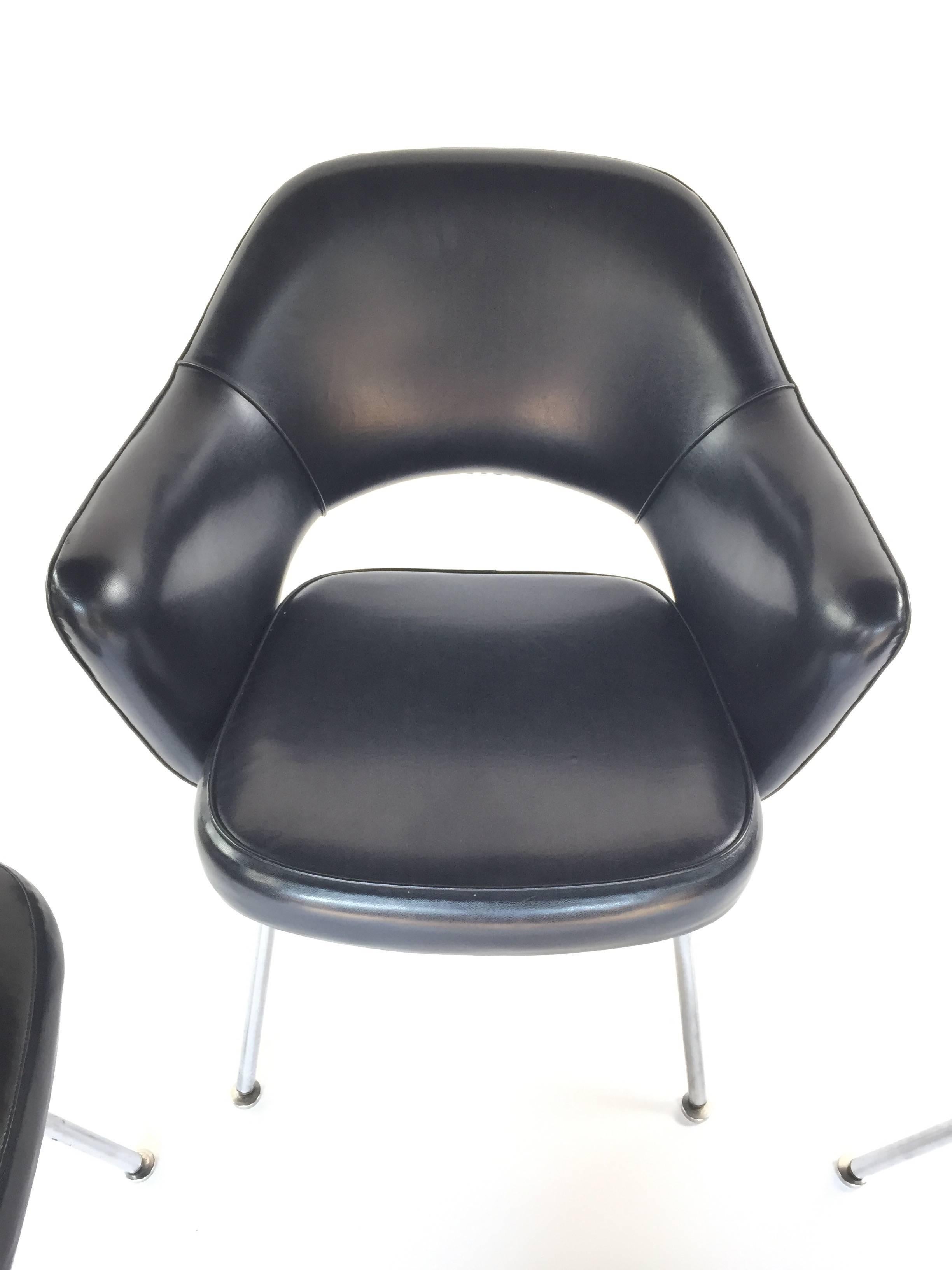 Absolutely pristine original set of four early bow tie label Eero Saarinen Executive Chairs. Perfect steel legs and black vinyl. Supple to the touch and full bodied resilient foam. Two chairs with arms, two side chairs.