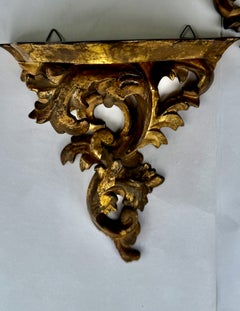 Coppia di mensole da parete in legno dorato intagliato in stile rococò con volute d’acanto, Italia, primi anni del XX secolo.