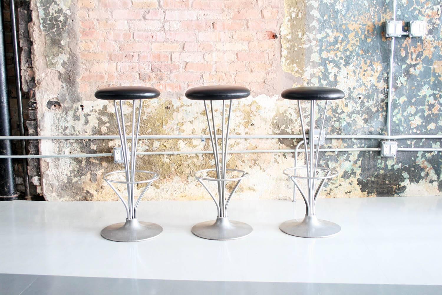 Set of three bar stools designed by Piet Hein for Fritz Hansen, 1962, Denmark. 
Super sturdy and comfortable aluminum and chromed steel construction with original black leather seats. Signed Fritz Hansen.
 
