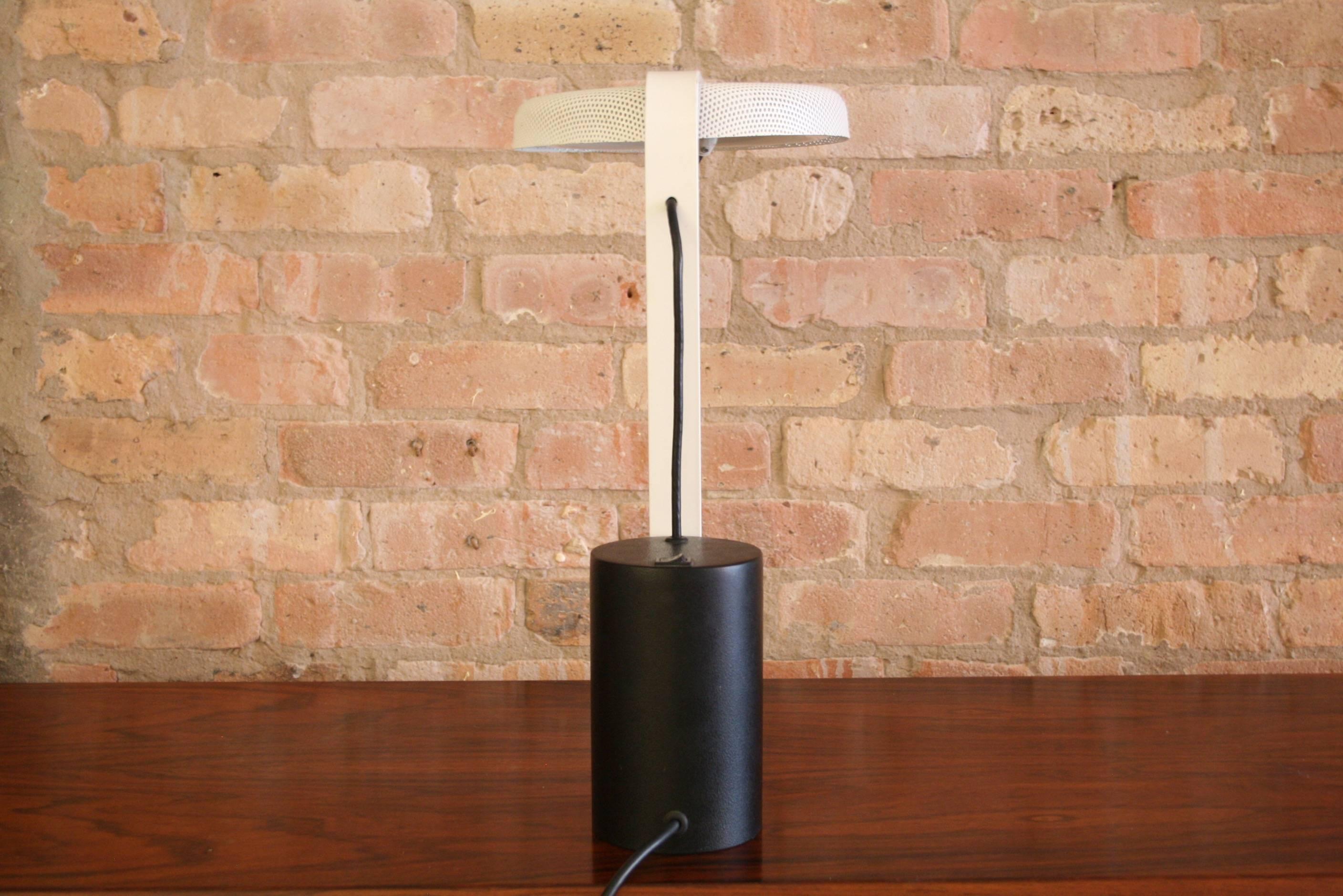 Ron Rezek black and white 110 Table Lamp. Rare fluorescent desk lamp with white enameled metal perforated shade and black cylindrical base. Utilizes 6 inch circular fluorescent bulb.