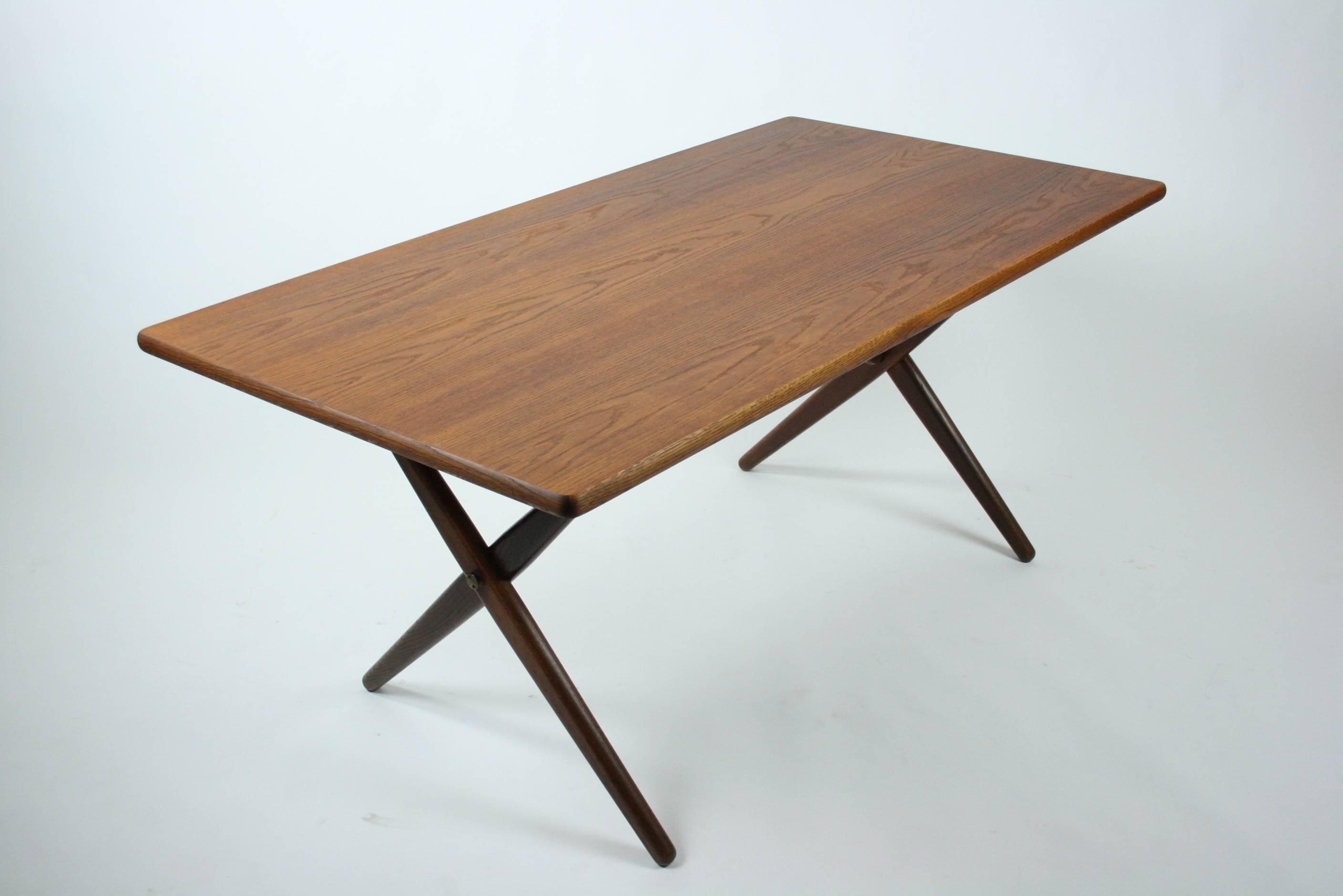 Rare Wegner design produced by Andreas Tuck / Denmark. 

The table legs are made of solid teak and supported by two brass X-brackets. The tabletop is also teak. The tabletop and legs have been restored.