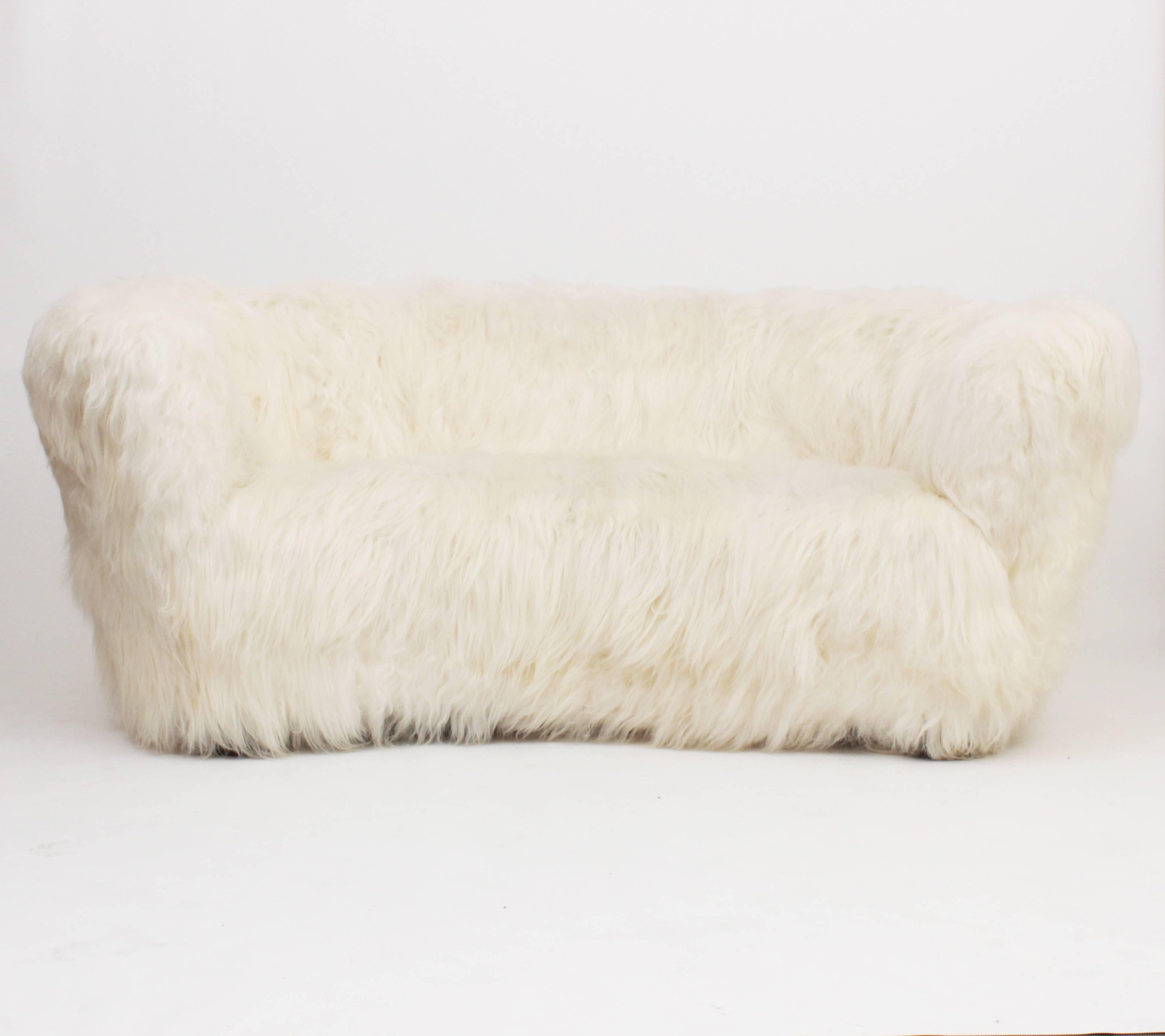 Three-seat curved sofa by Slagelse Mobelvaerk. newly upholstered in natural white Icelandic sheepskin, Denmark, circa 1940.
Wooden structure and feet.