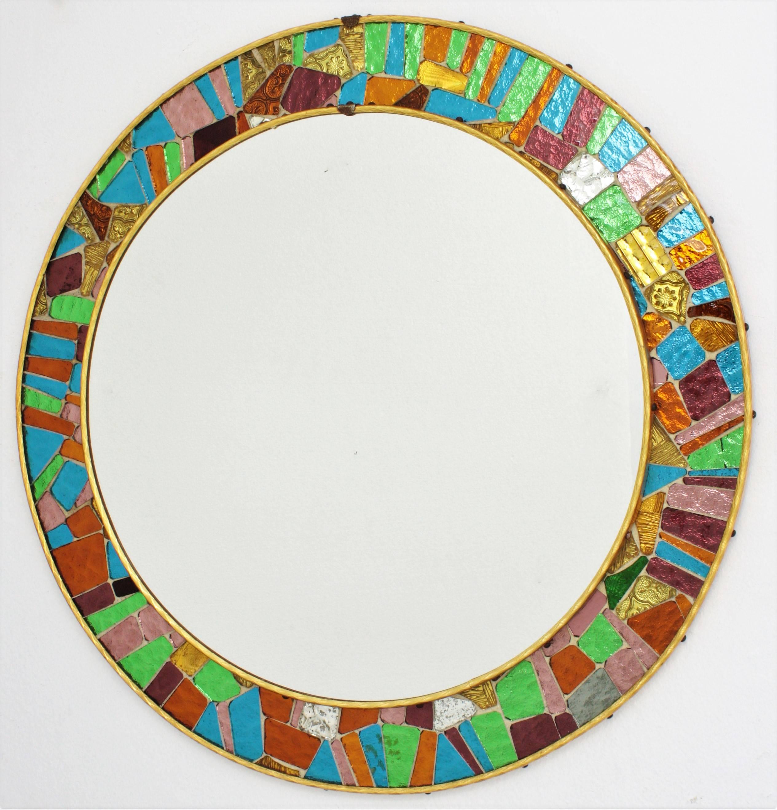 Amazing circular mirror from the mid-20th century period framed with small pieces of colorful mirrored glass creating an stunning mosaic frame. In the style of Gaudí Trencadís technique.
Small mirrored hand-cut-glass tiles in blue, green, gold,
