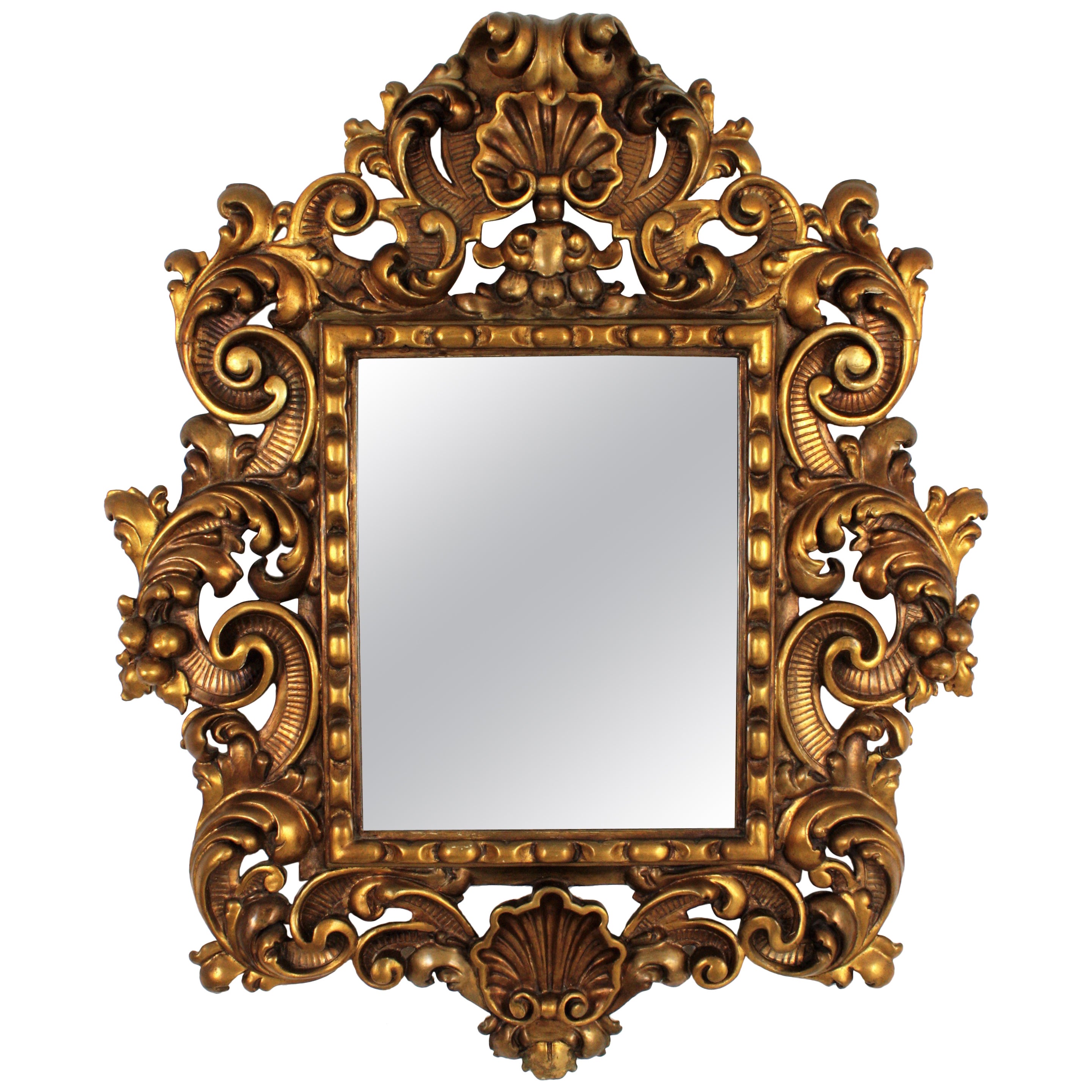 A gorgeous Spanish Rococo style mirror finely carved with beautiful naturalistic motifs. Spain, 1930s 
One of a kind spanish carved wall mirror
Gold leaf giltwood with an excellent aged patina. This exquisite frame has a richly decoration with